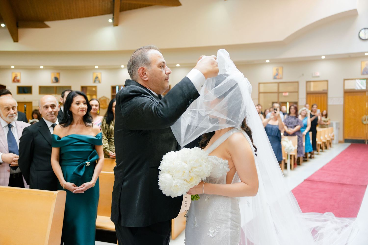 Emotional moment as the bride's veil is lifted during the wedding ceremony in a church.