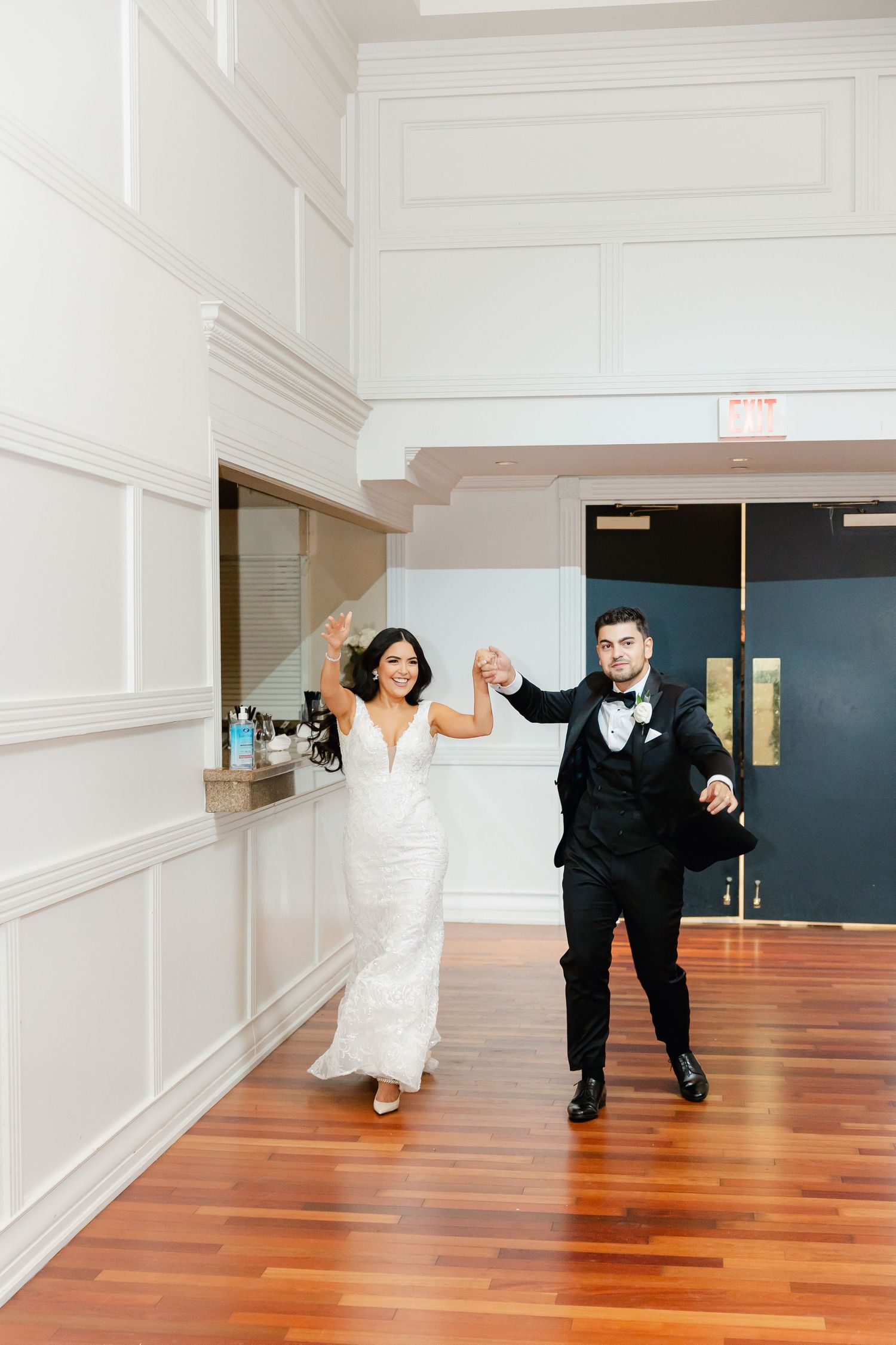 Wedding celebration moment on hardwood floor in bright indoor venue.