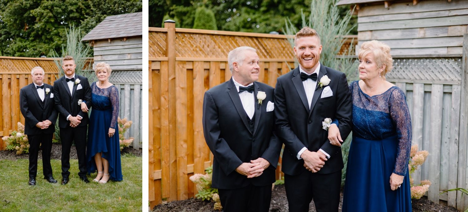 Wedding party members in formal attire stand against wooden fence during outdoor celebration.