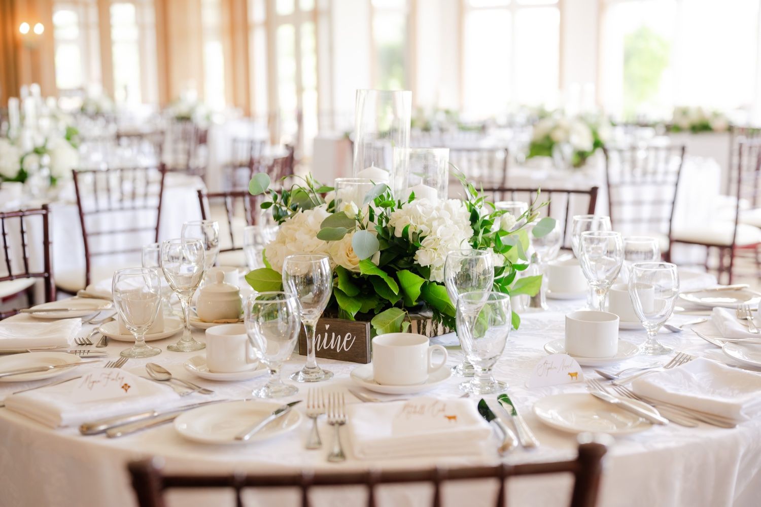 Elegant round reception table with white floral centerpiece and formal place settings.