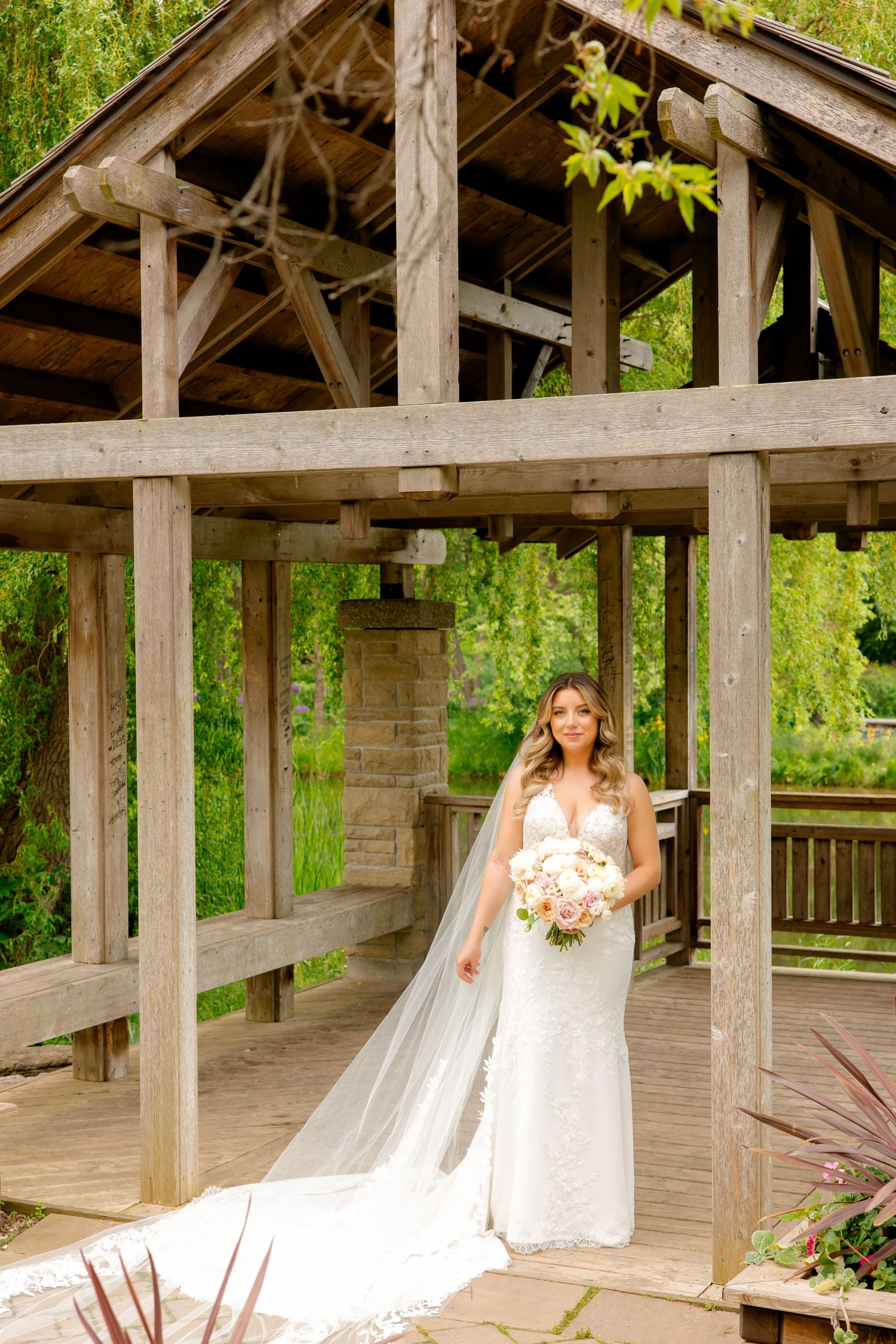 Elegant bridal portrait featuring a long cathedral veil in a wooden pavilion.