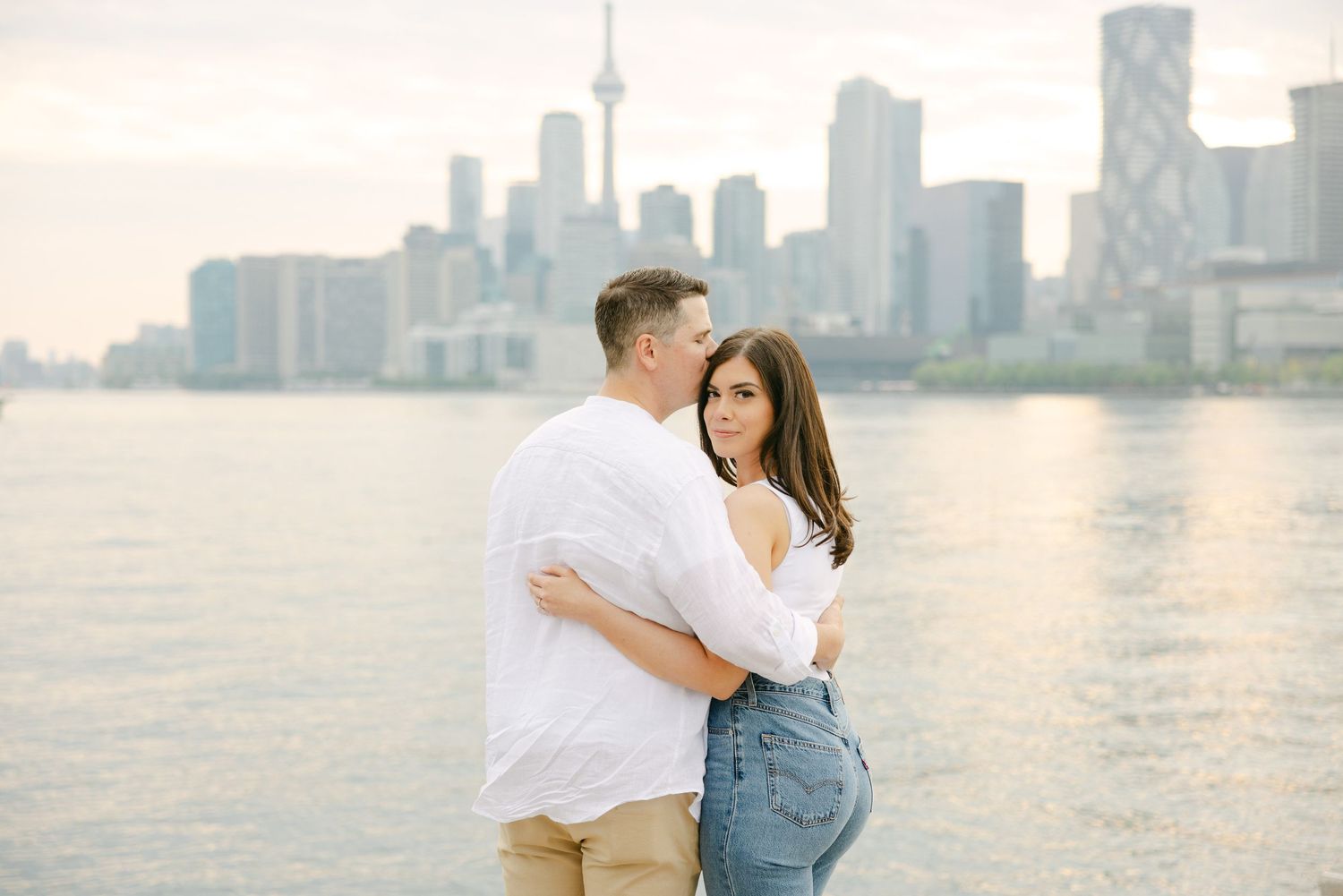A romantic waterfront portrait with Toronto's distinctive skyline creating a dreamy backdrop.