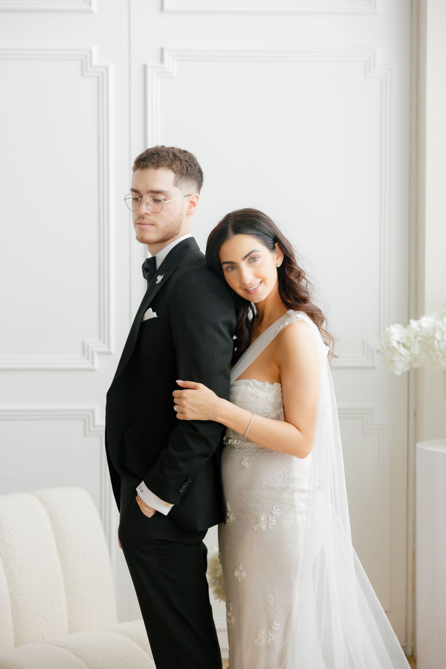 A classic wedding portrait featuring a couple in traditional attire against a bright white backdrop.