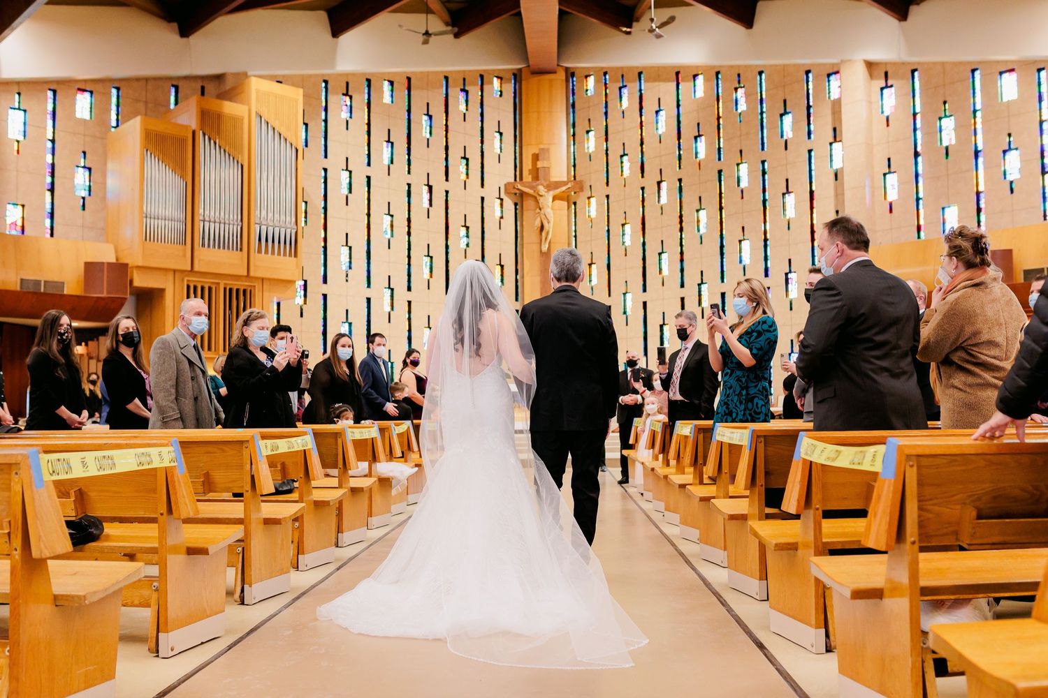Wedding ceremony in a church with hanging decorative lights and wooden pews.