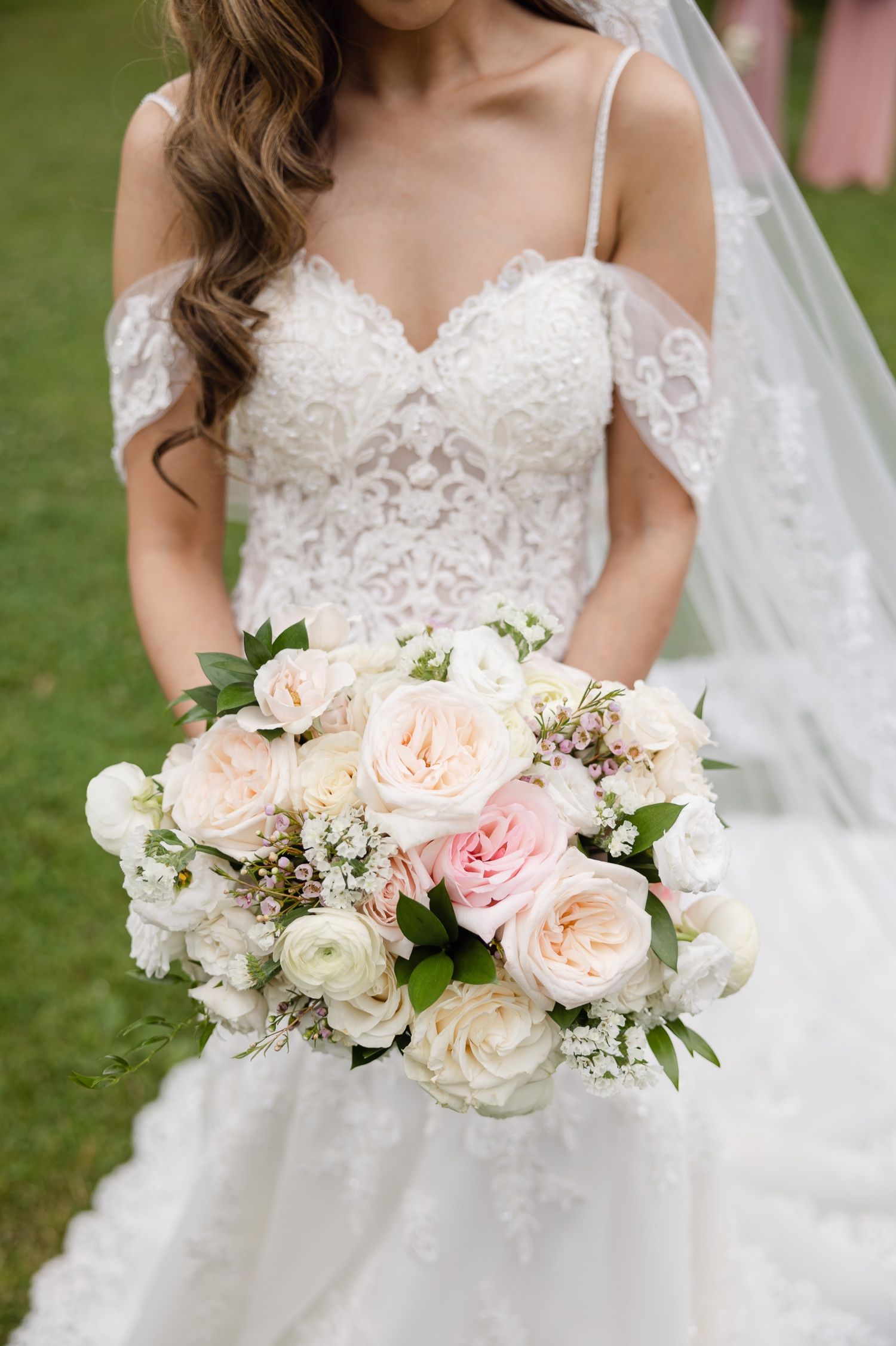 Delicate lace wedding dress bodice paired with romantic bouquet of blush and white roses.