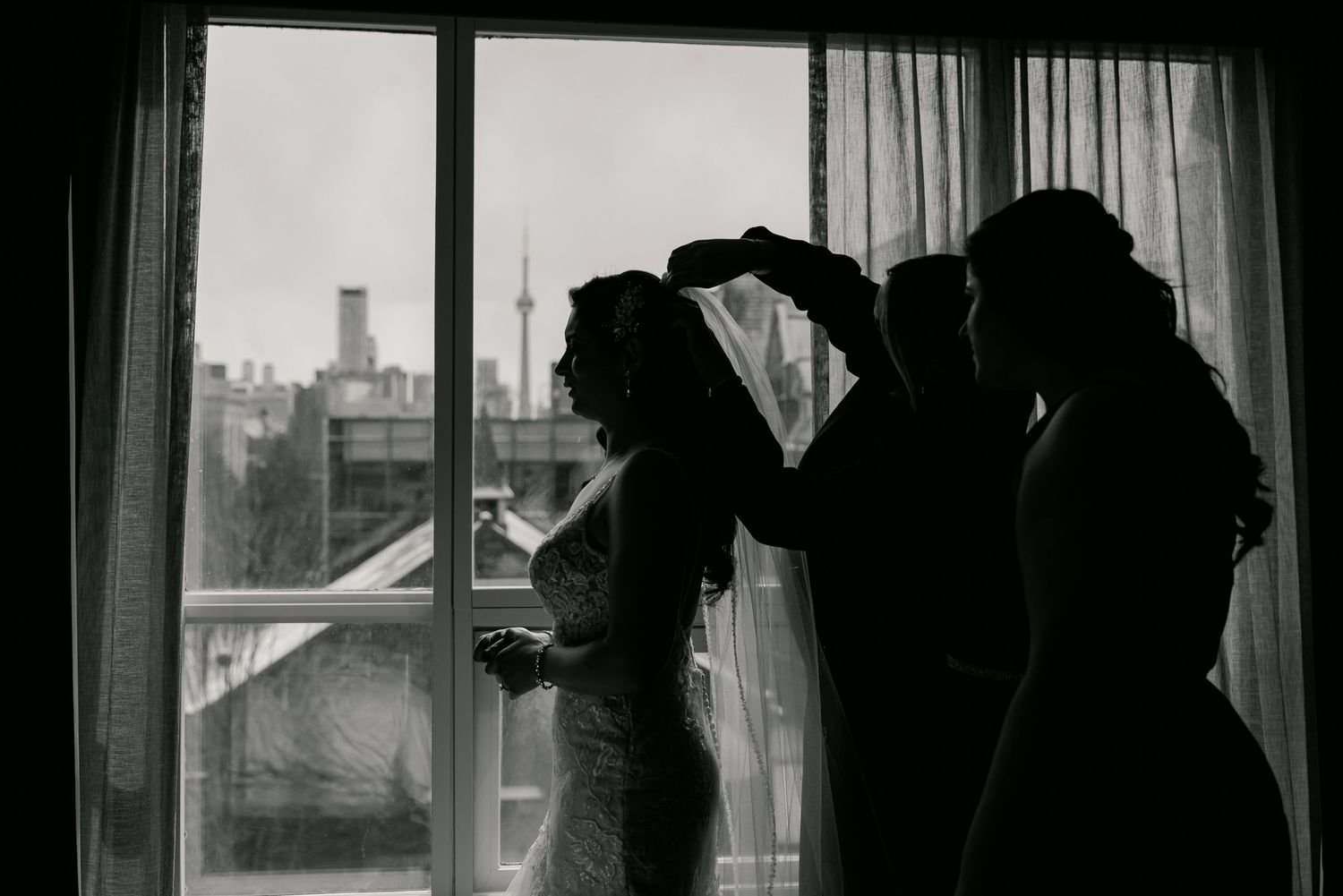 Silhouette of bridal preparation against window showing wedding day getting ready moments.