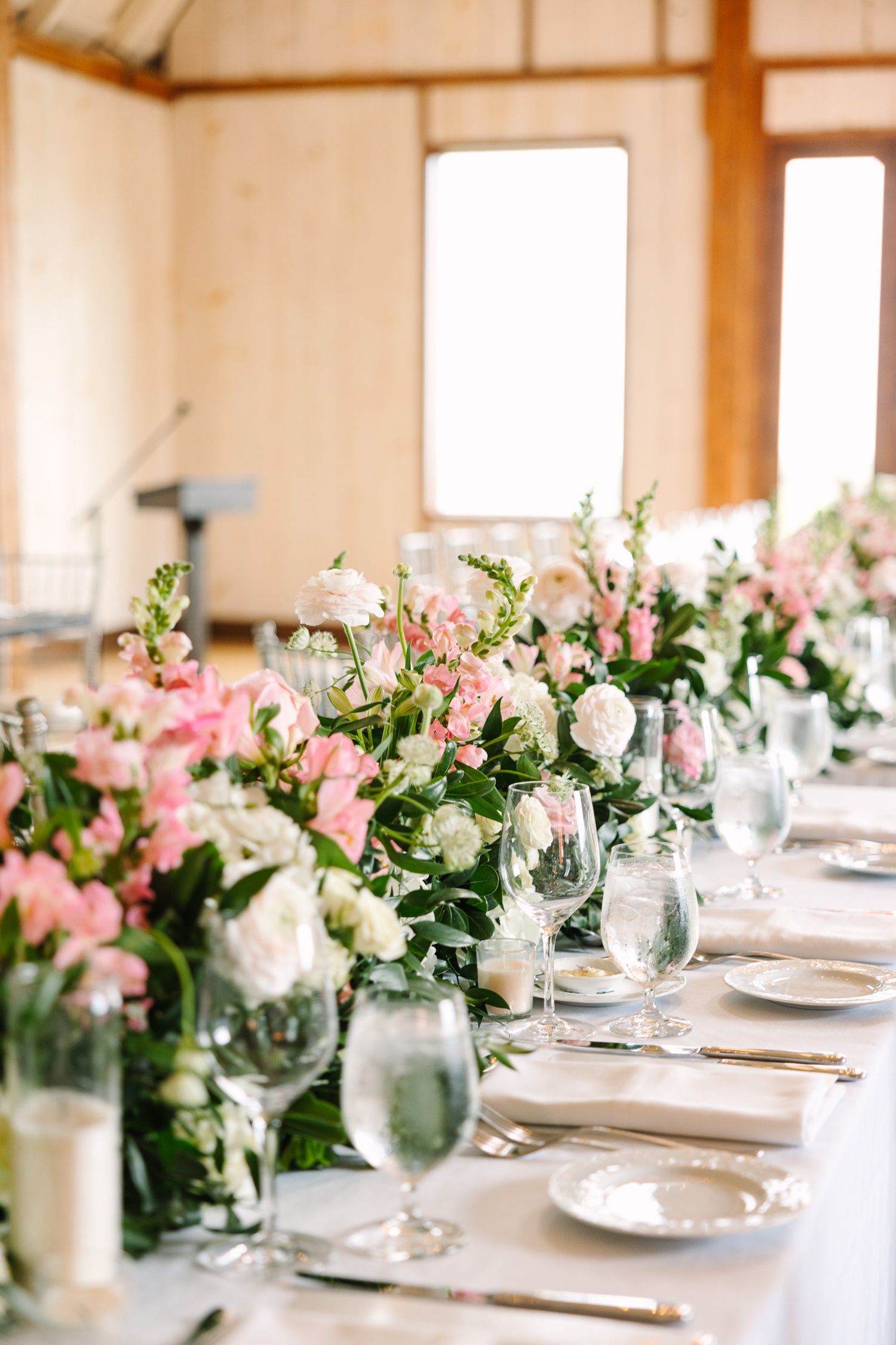 Elegant table setting with pink and white floral arrangements and crystal stemware.