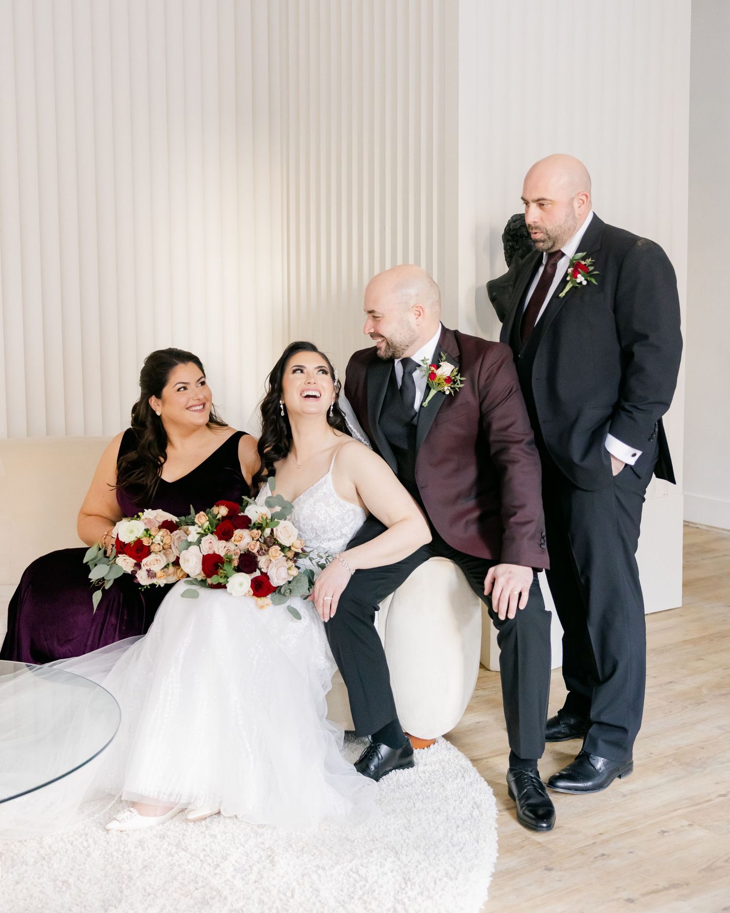Wedding party gathered for formal photos featuring burgundy and black formal attire.