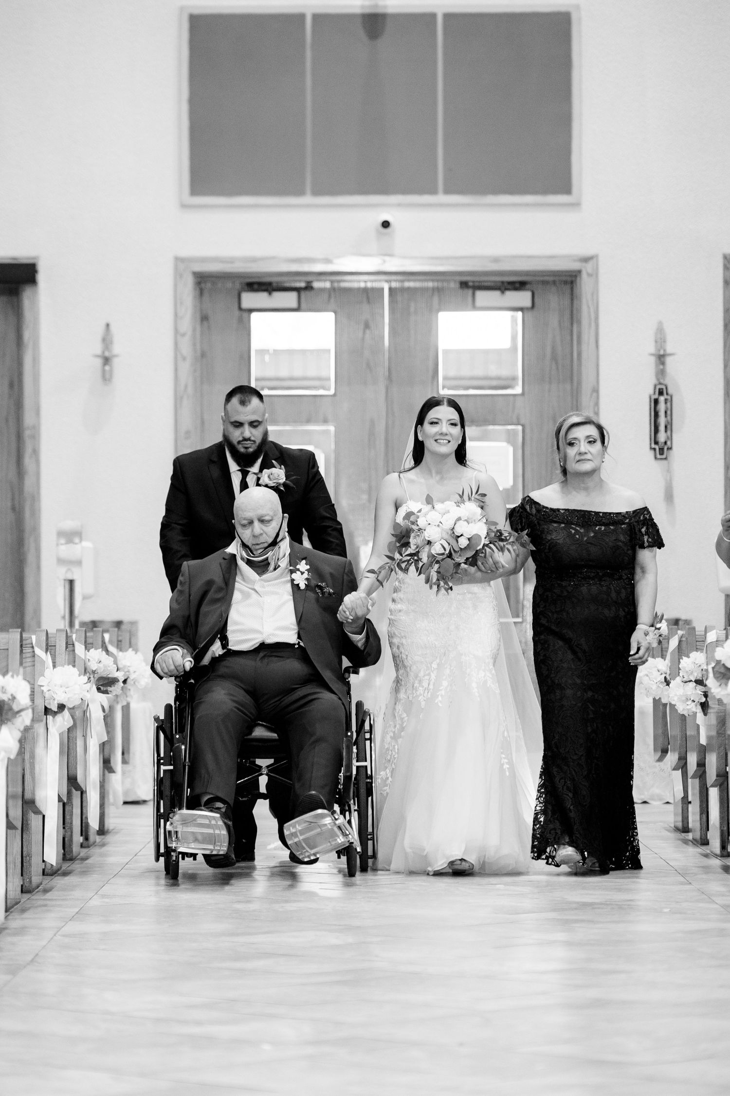 Black and white photo of a wedding procession down a church aisle with wheelchair accessibility.