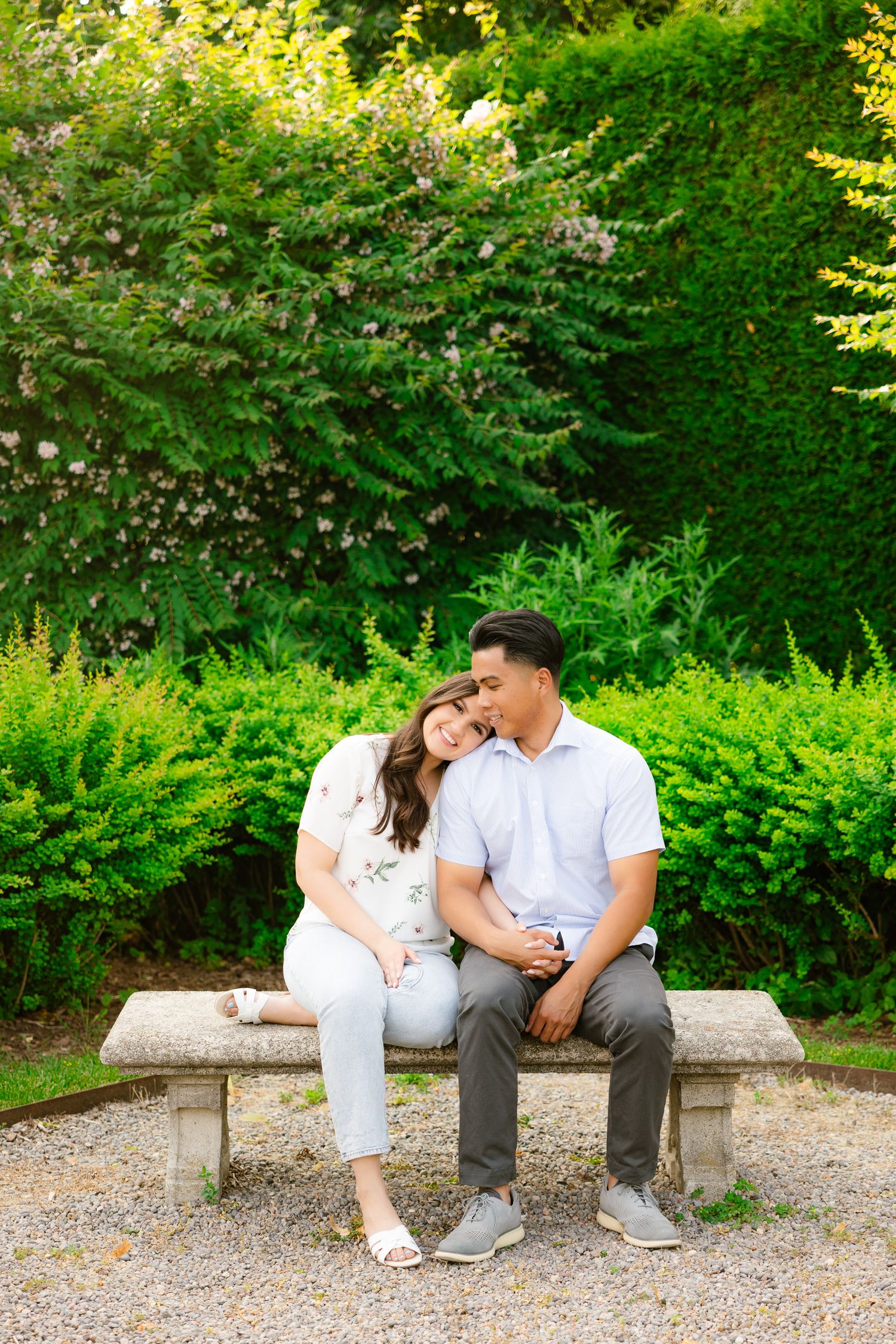 A romantic moment captured between a couple on a stone bench in a verdant garden setting.