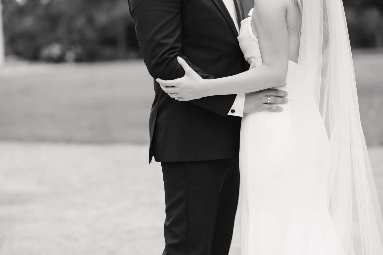A romantic black and white wedding photo showing a couple embracing in formal attire.