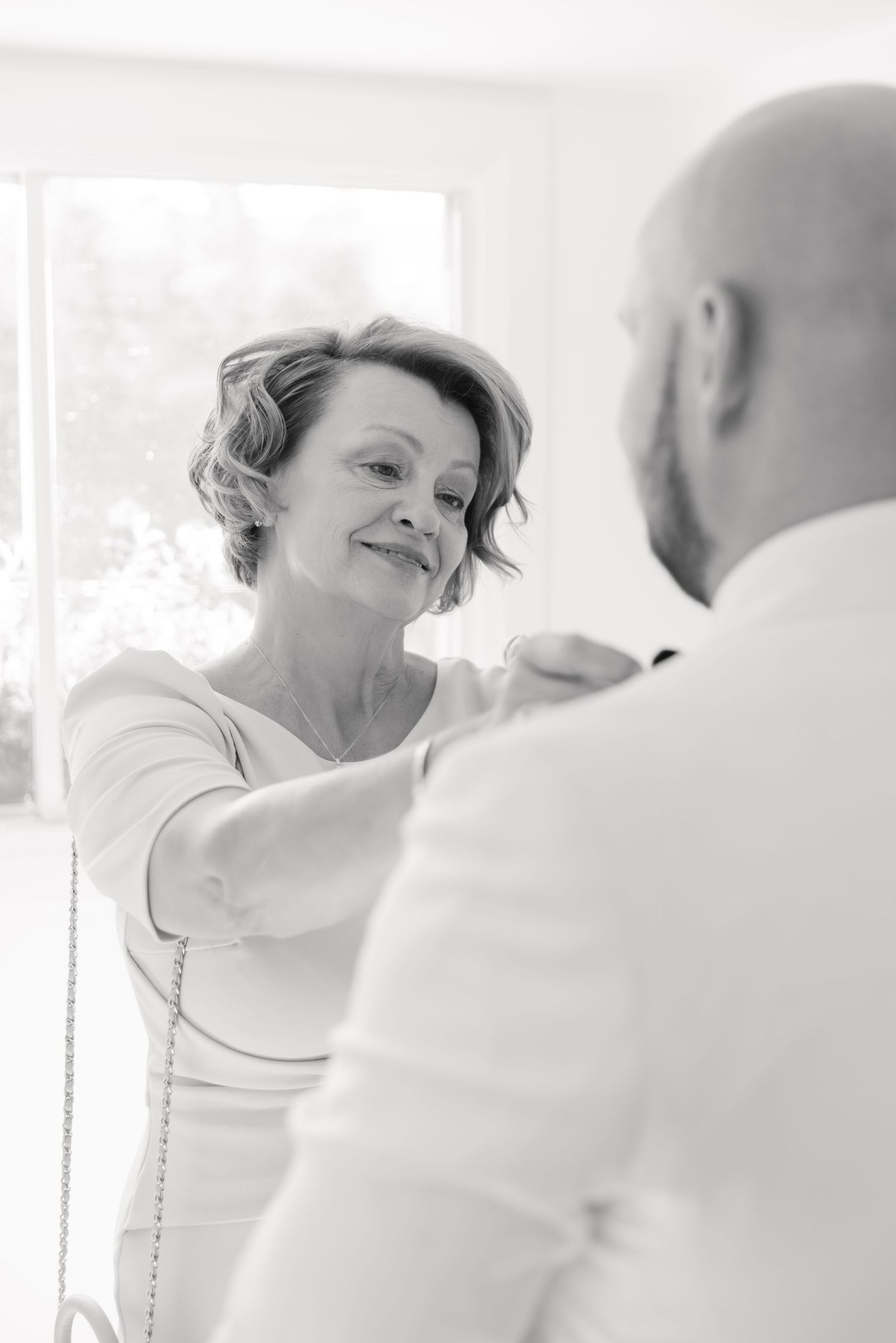 A tender moment captured during wedding preparations in a sunlit room.
