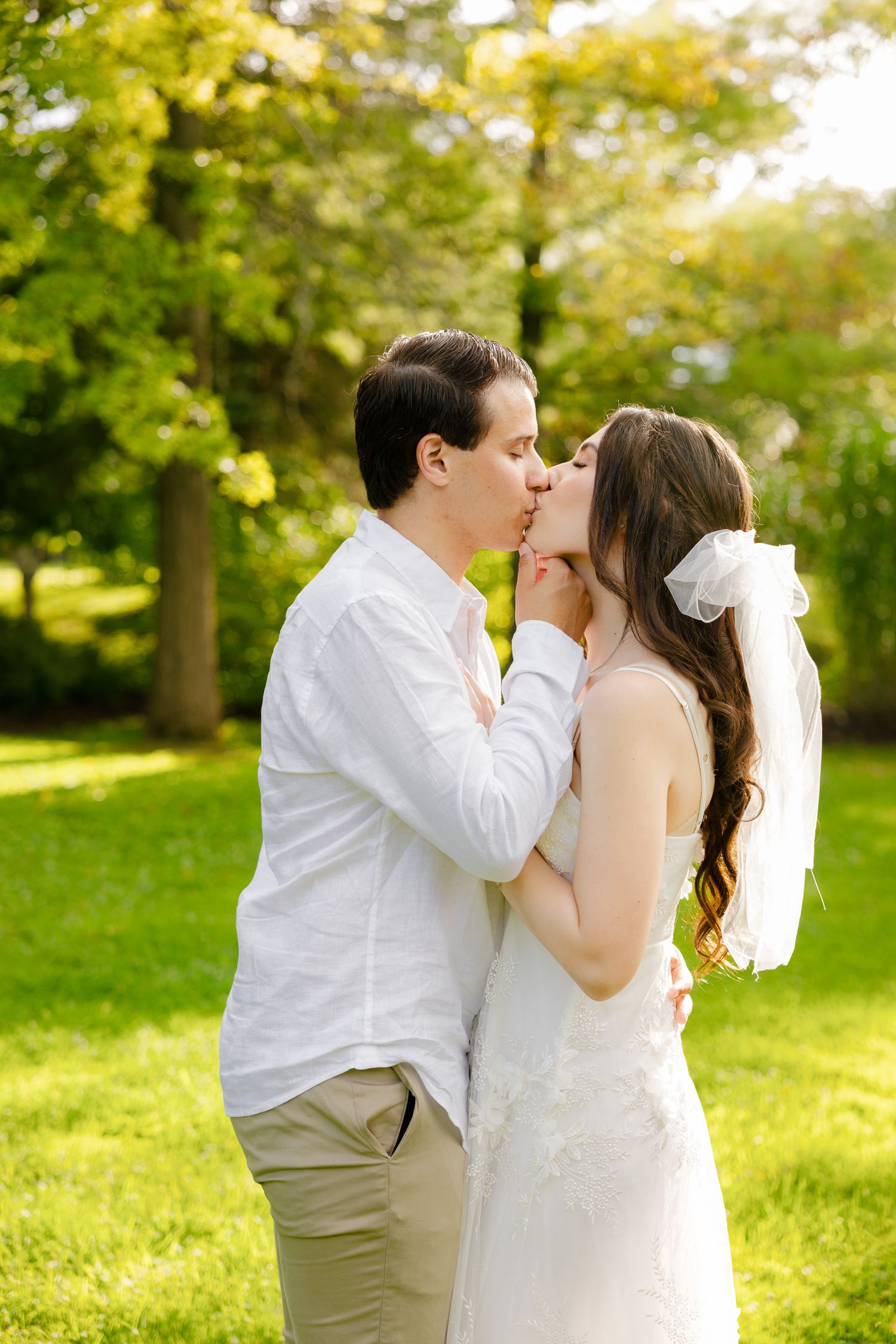 Sunlit garden wedding portrait capturing an intimate kiss between the couple.