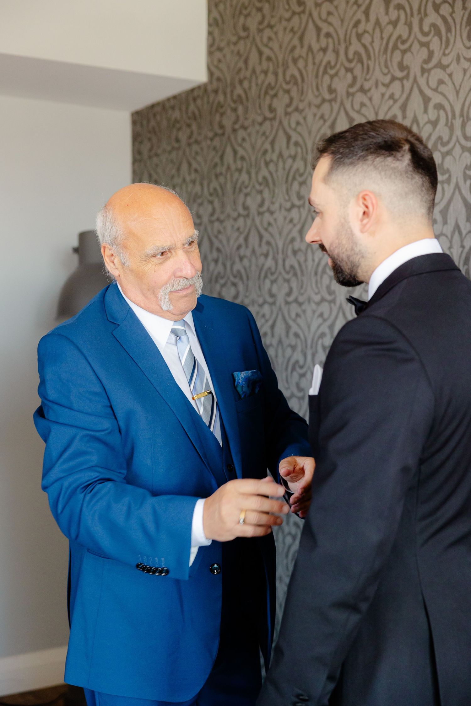 An emotional pre-wedding moment between family members in formal attire.