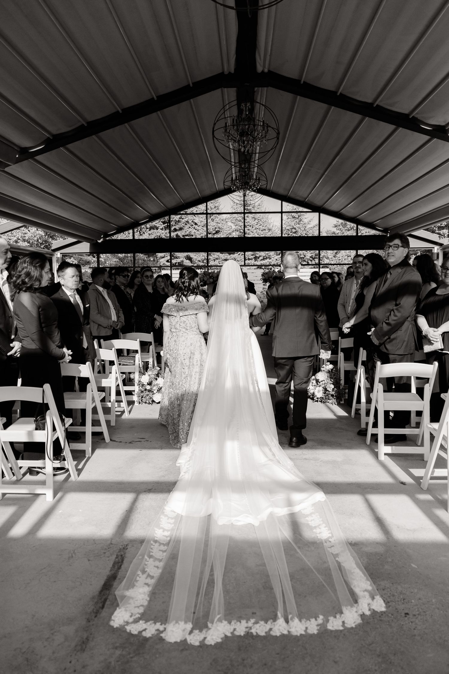 A cathedral-length lace veil trails behind during a wedding ceremony recessional.