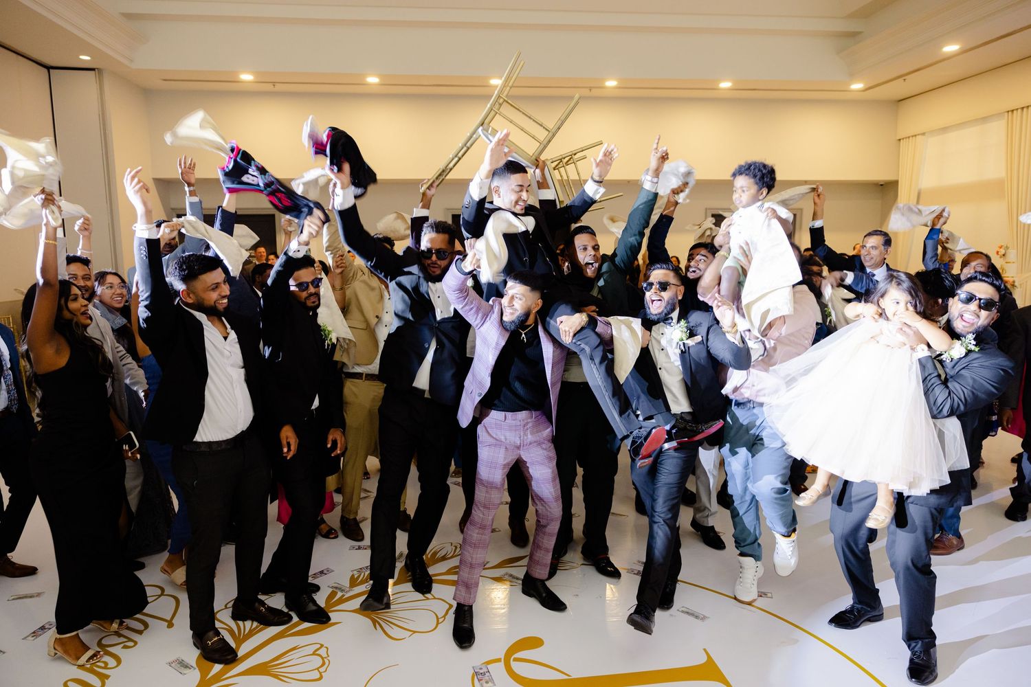 Wedding party and guests jumping and celebrating with high energy during reception festivities.