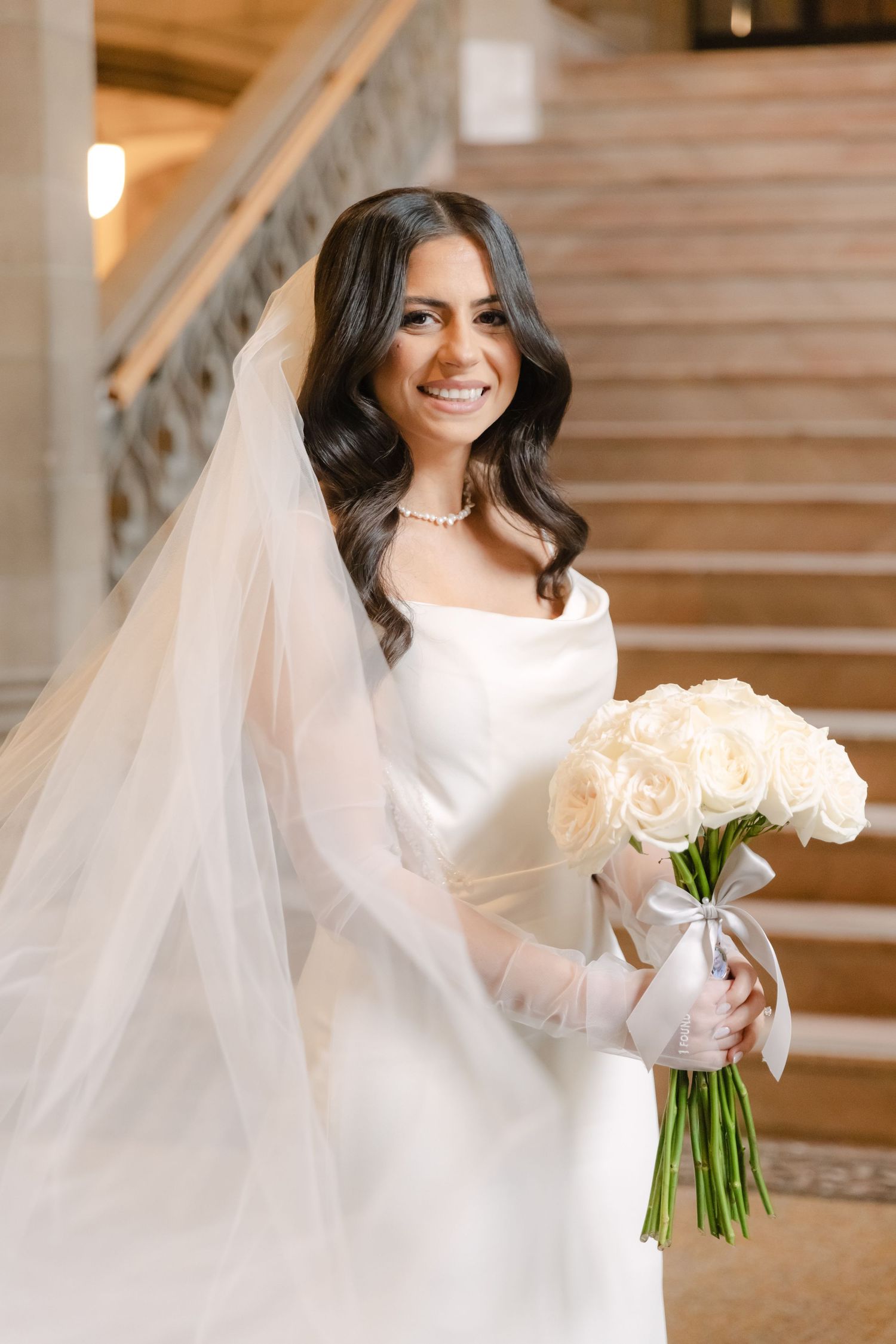 A joyful bridal portrait featuring a classic white gown and cream rose bouquet.