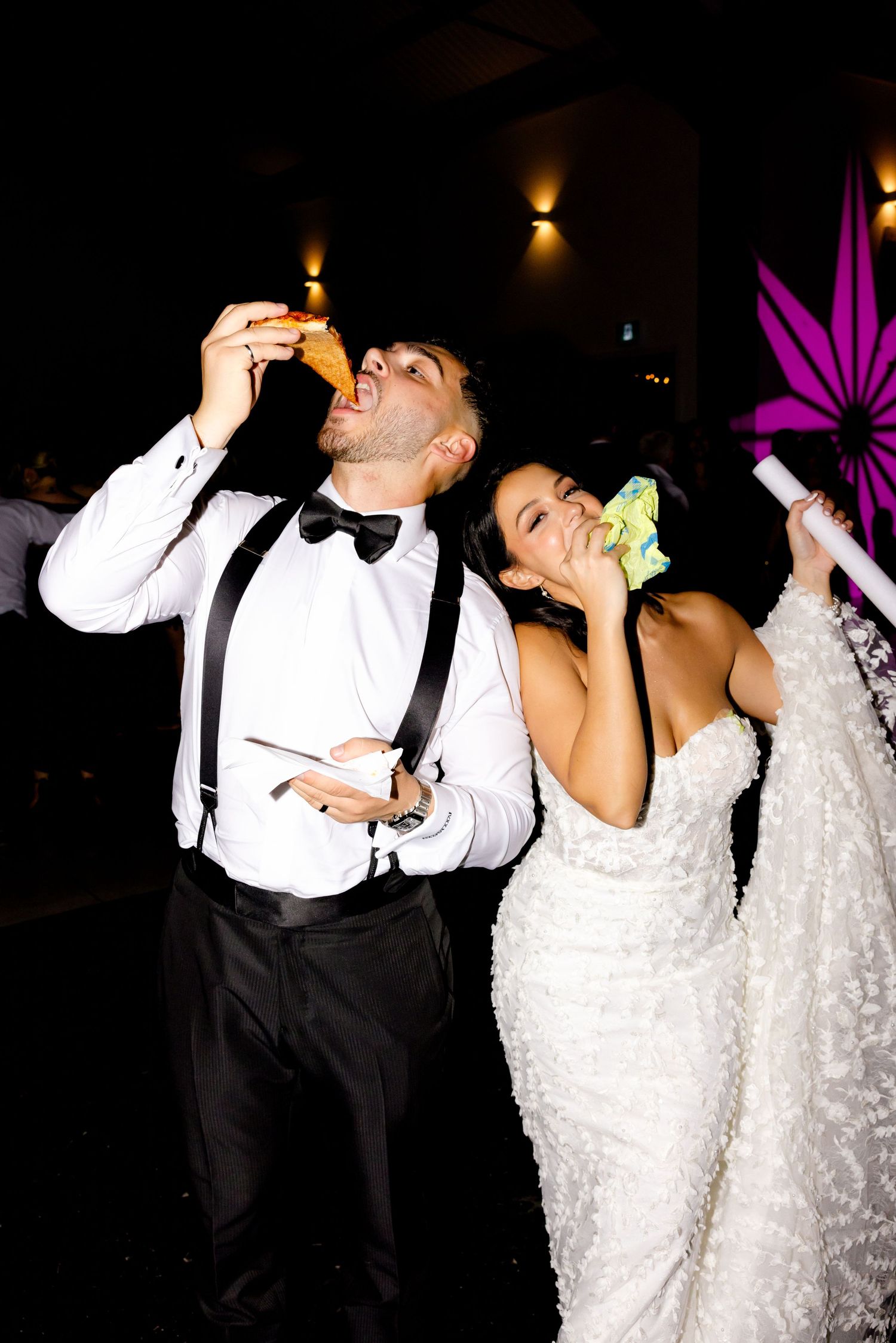 Wedding couple enjoying drinks and celebrations at dimly lit reception venue.