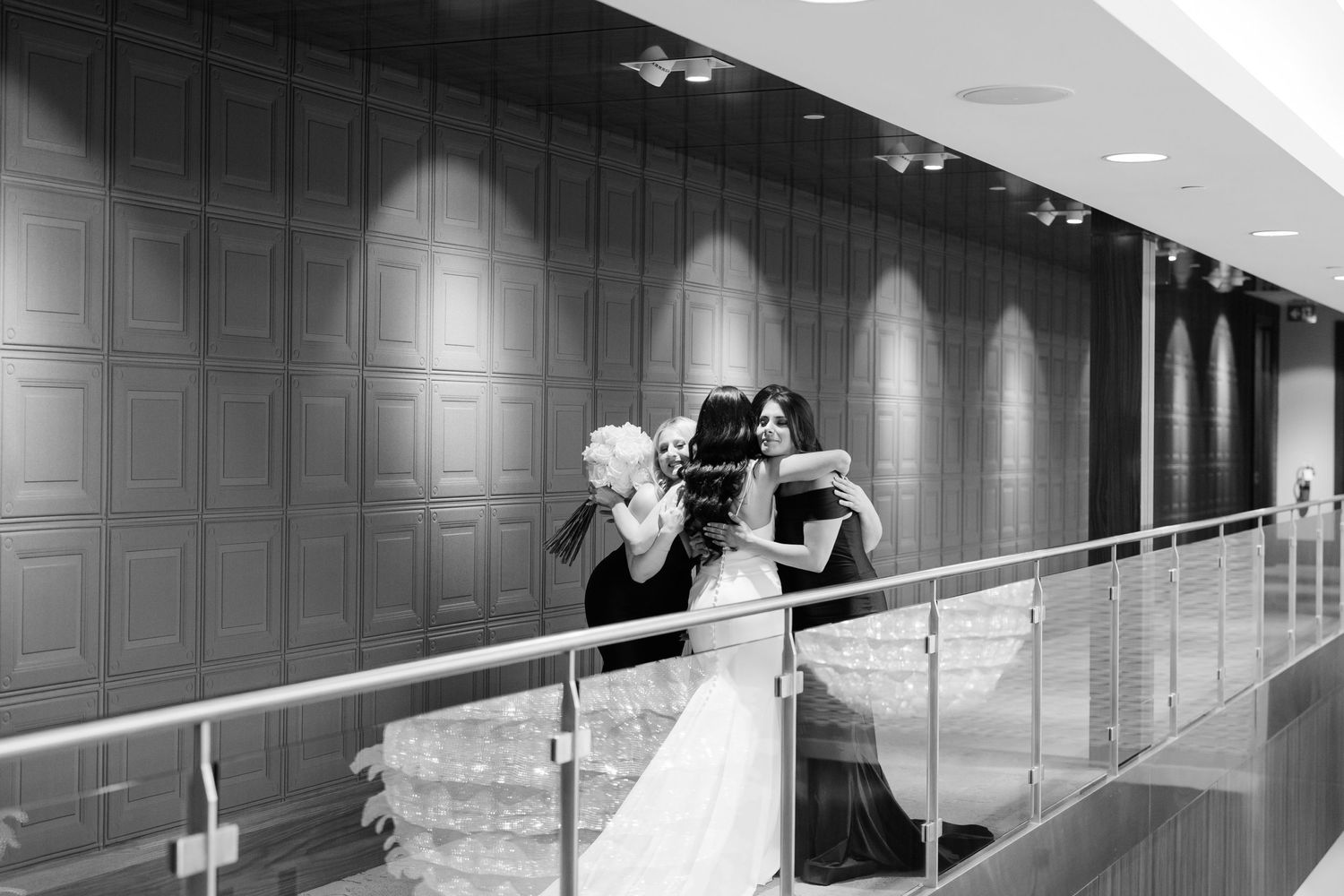 A black and white candid moment of bridesmaids having an emotional first look with the bride.