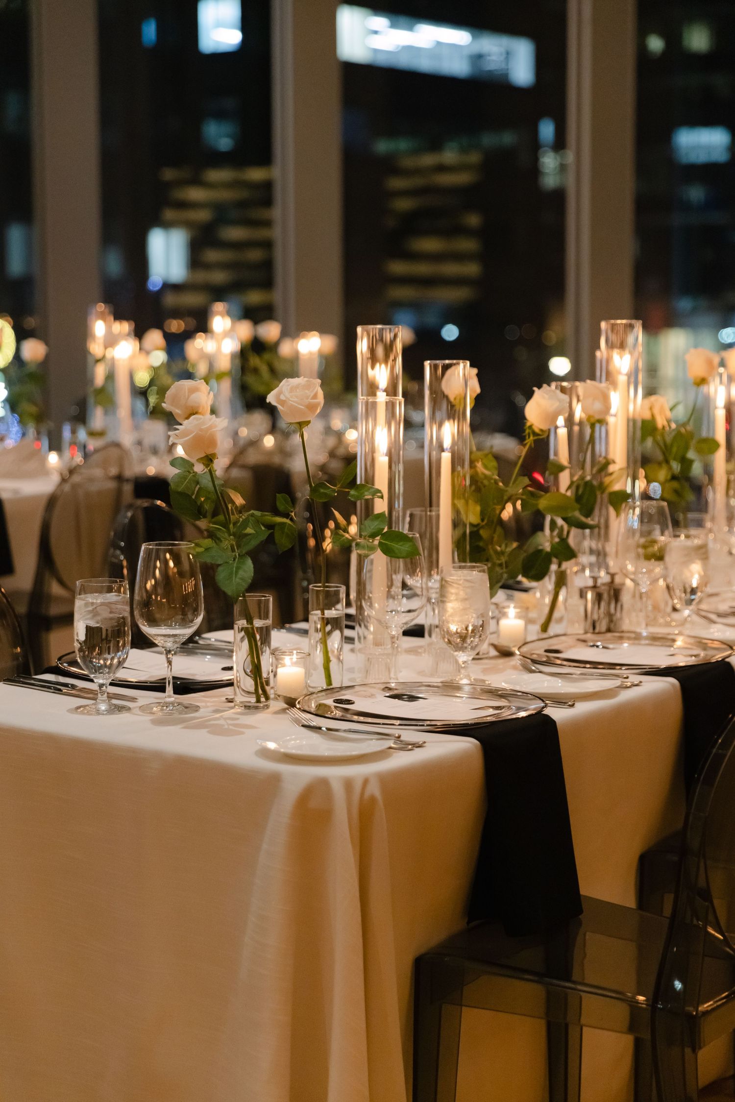 Elegant wedding reception table setting with white linens, candles, and floral centerpieces.