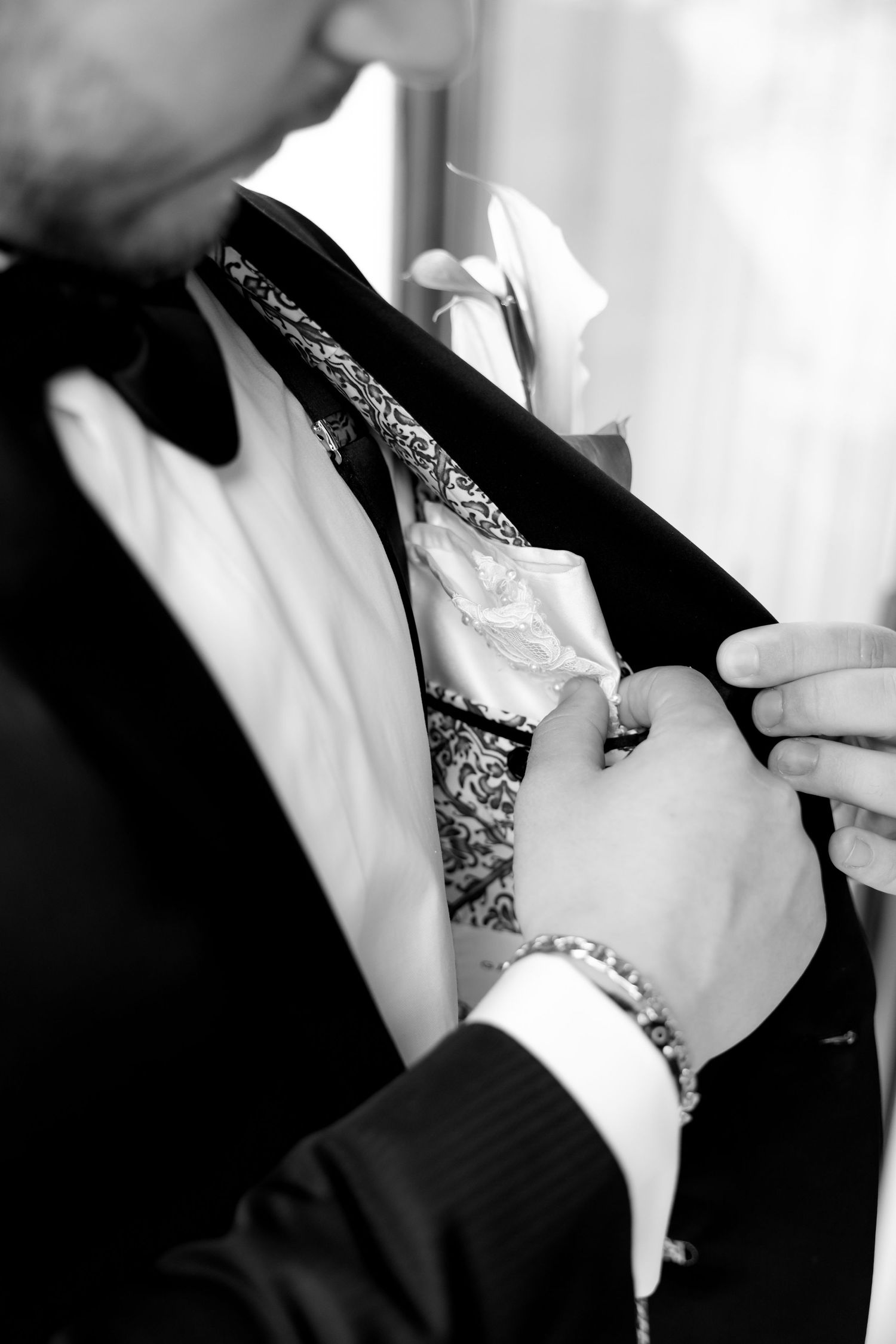 Black and white detail shot of hands adjusting a patterned tie.
