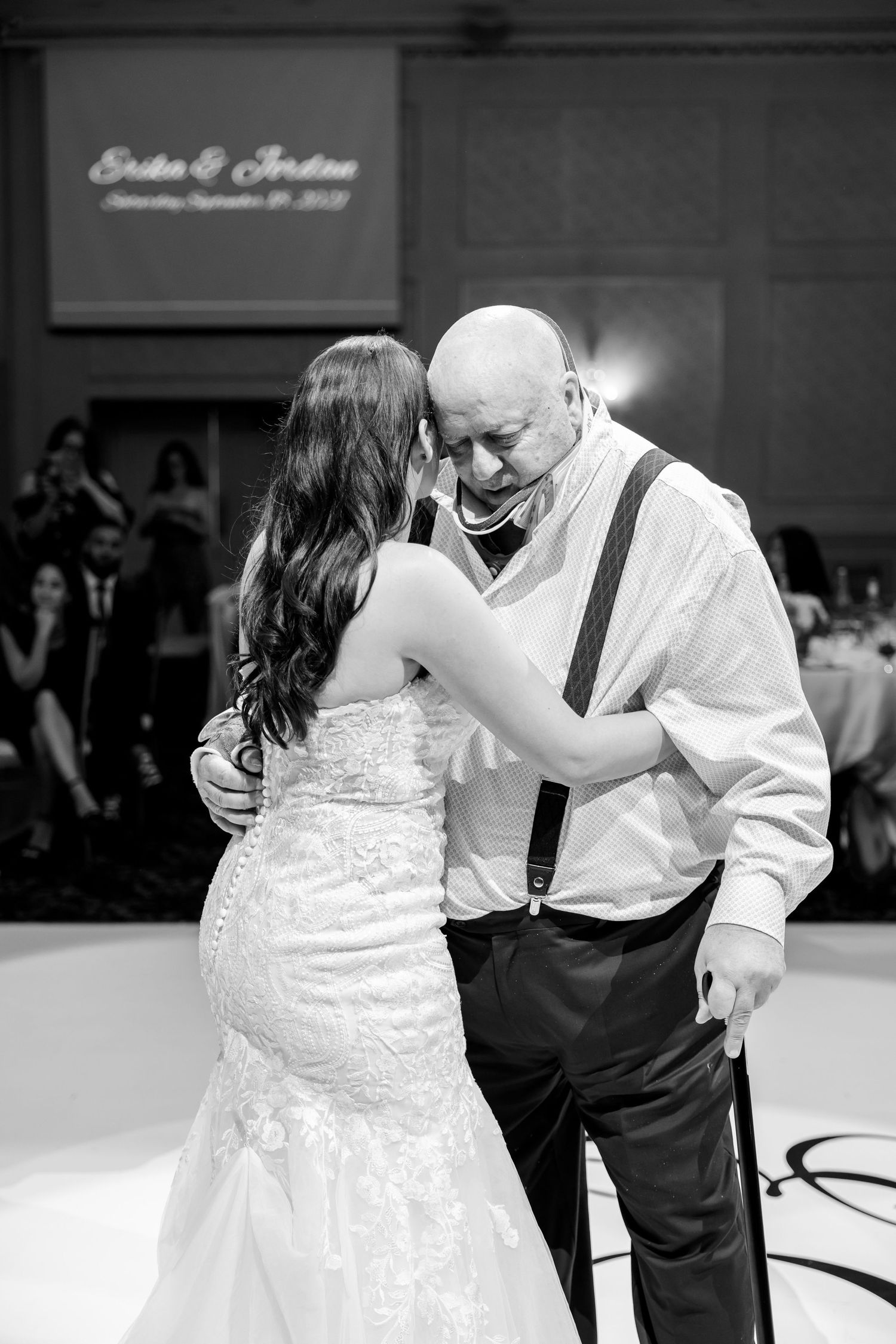 An intimate moment shared during a wedding dance in an elegantly decorated reception hall.