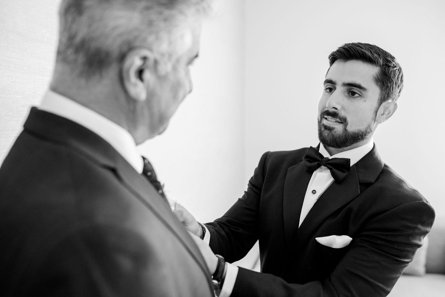 Two men in formal attire having a conversation in black and white photography.