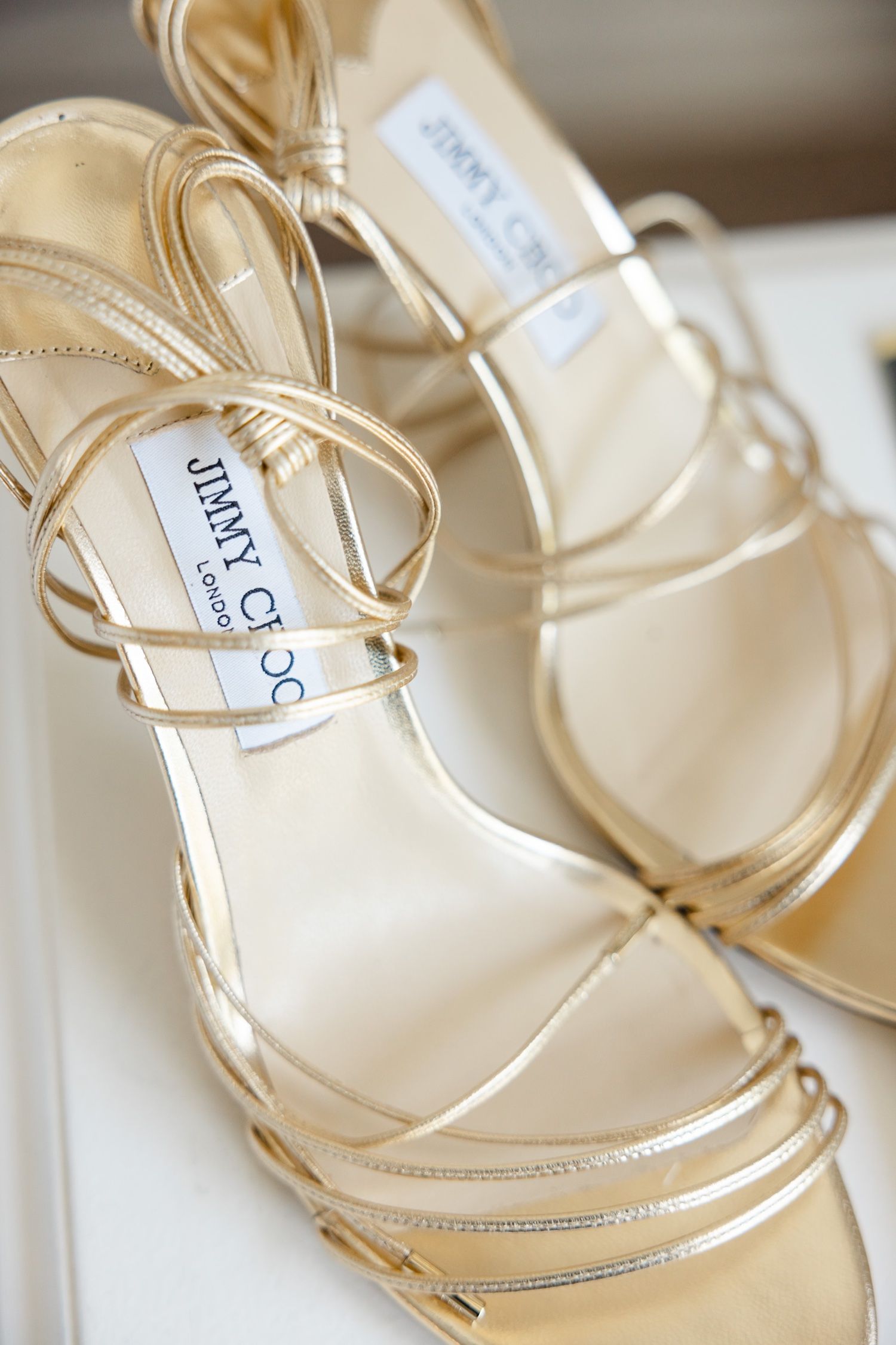 Metallic gold strappy wedding sandals displayed against white background.