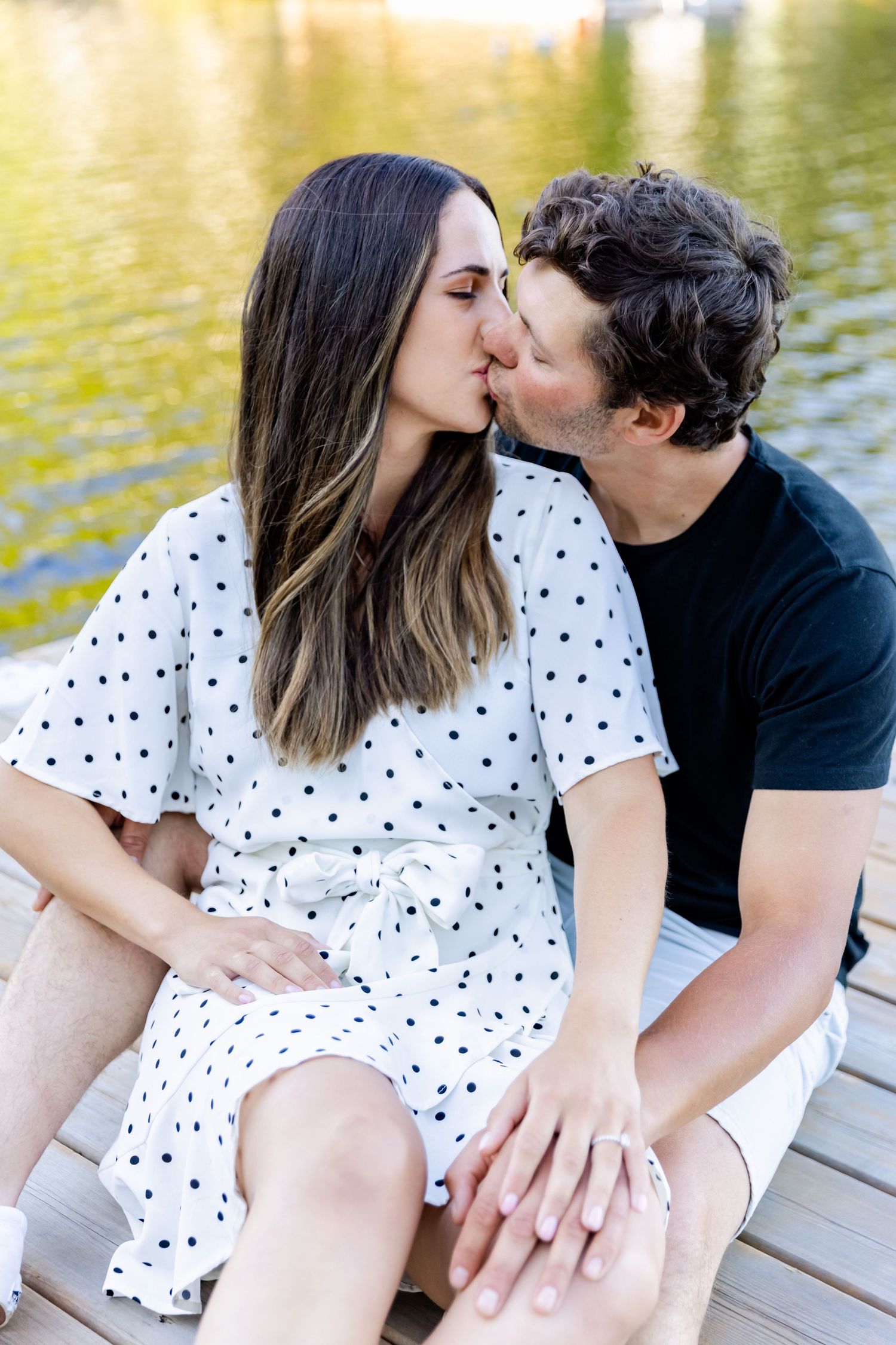 Romantic lakeside moment between couple on wooden dock during sunset.