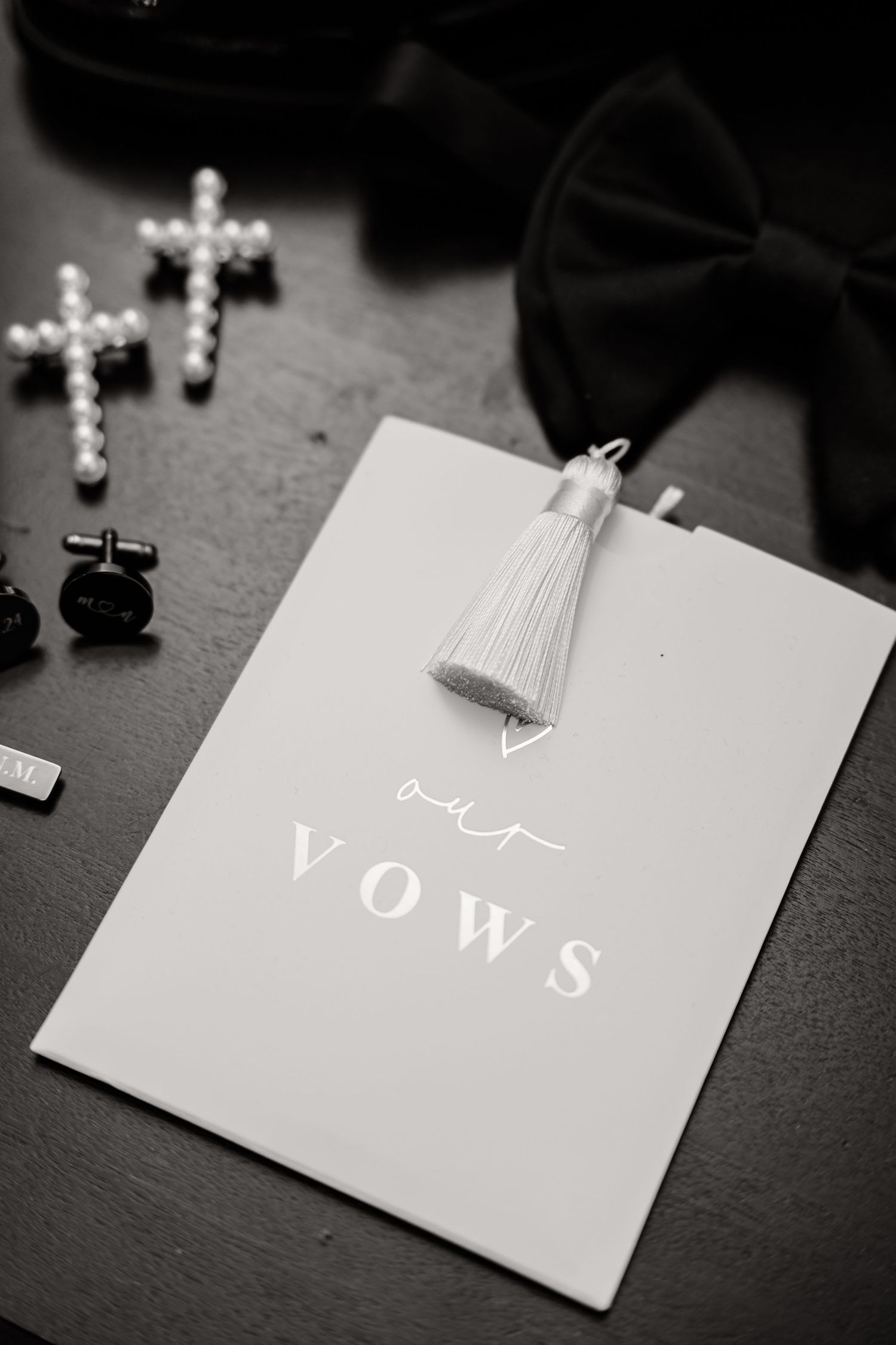 Black and white wedding vows card with pearl cross and tassel detail.