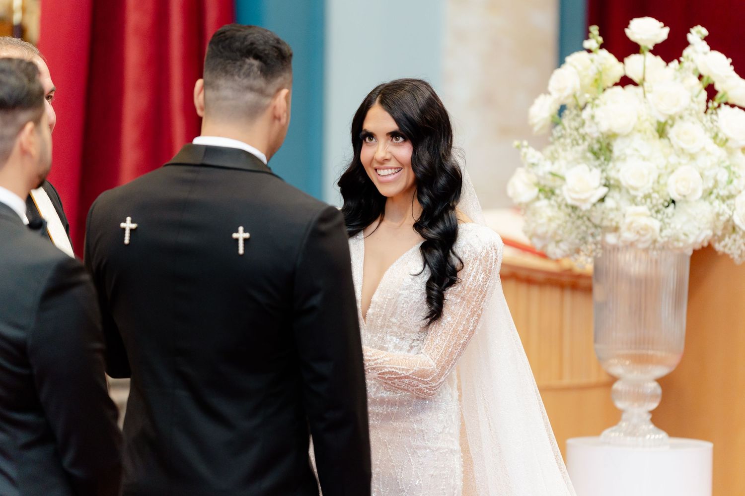 A couple exchanges vows at the altar with elegant white floral arrangements in the background.
