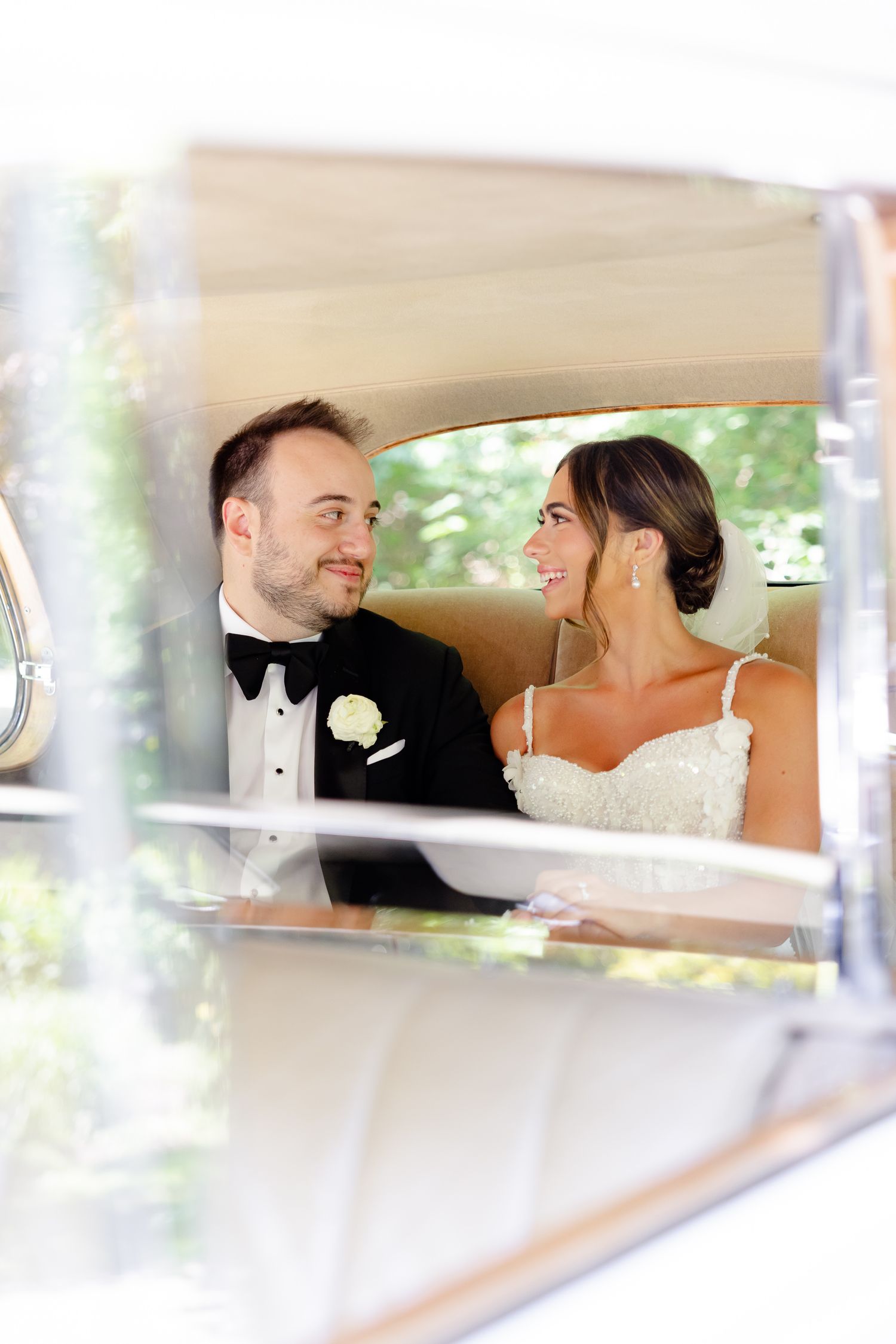 A couple shares a tender moment inside a classic white wedding car during their special day.