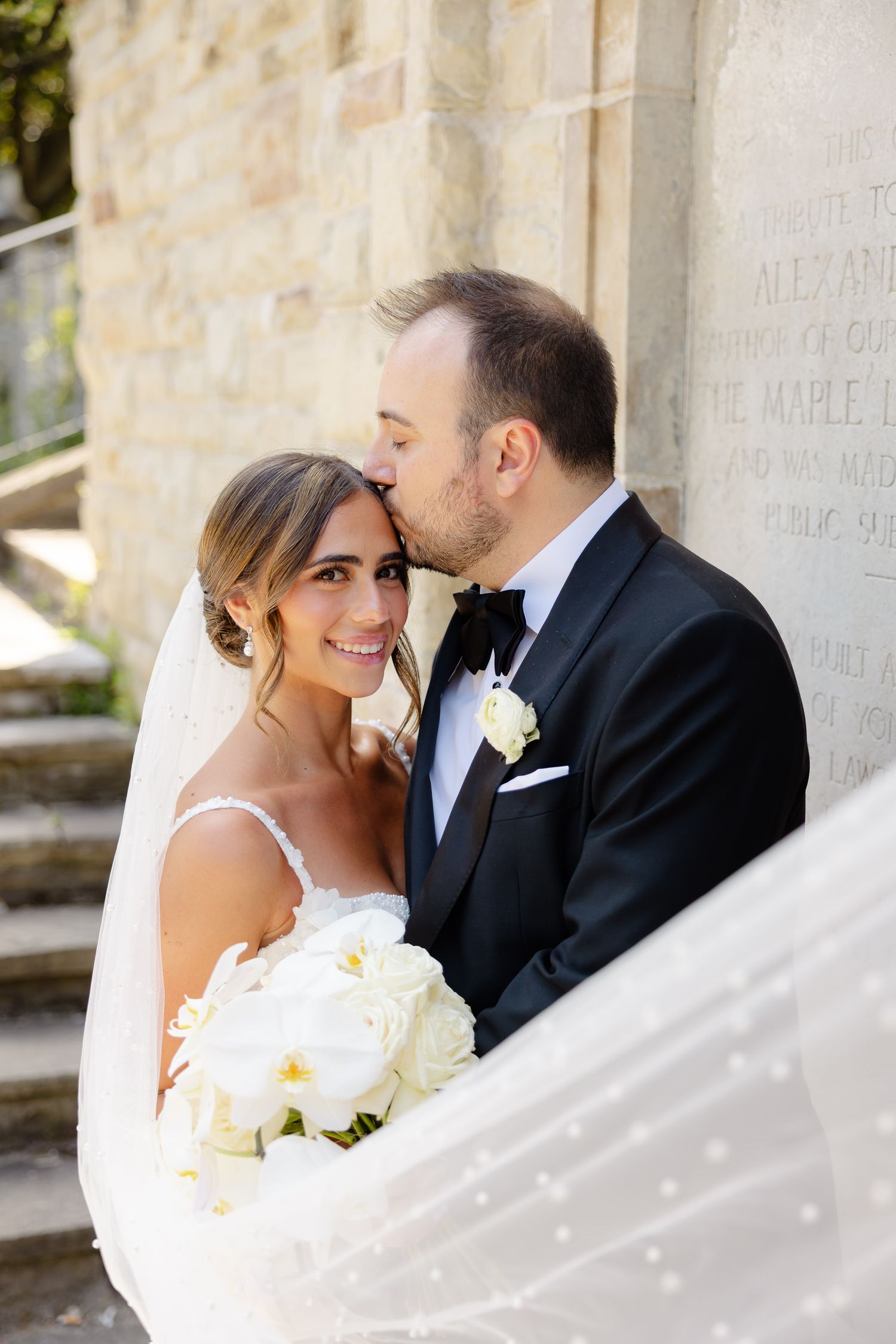 A romantic newlywed couple shares intimate moments in a series of wedding portraits against a stone wall background.