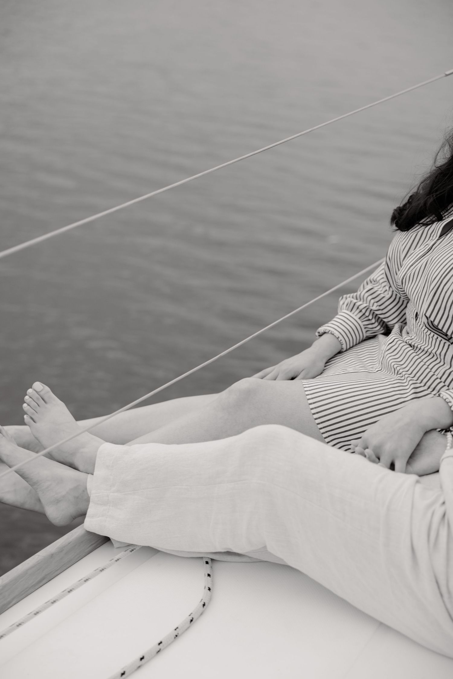 Person relaxing on a boat deck wearing striped clothing, with bare feet visible against a calm water background.