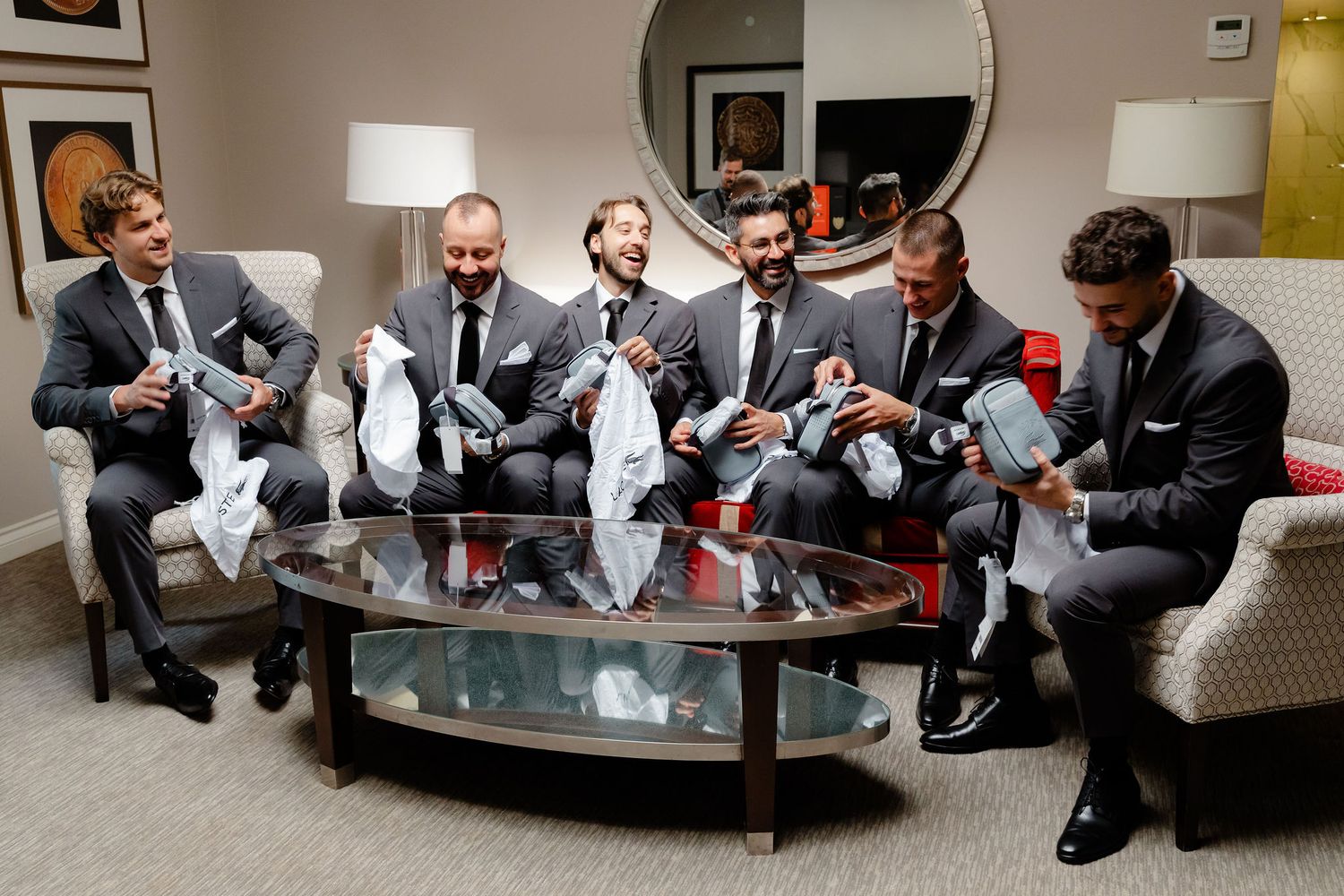 Groomsmen relaxing on couches during wedding preparations.
