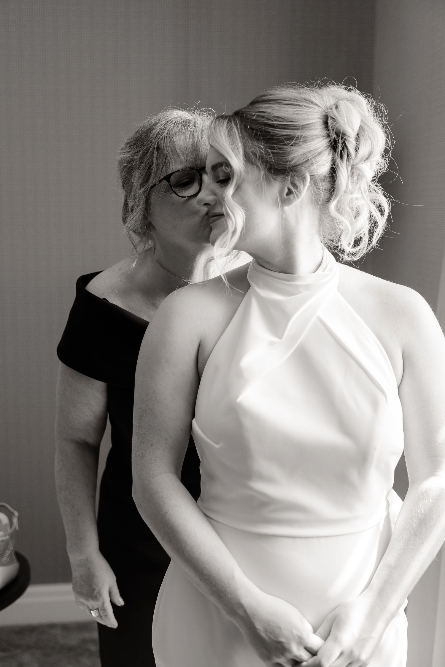 Black and white portrait of two people sharing an intimate moment in elegant formal attire.