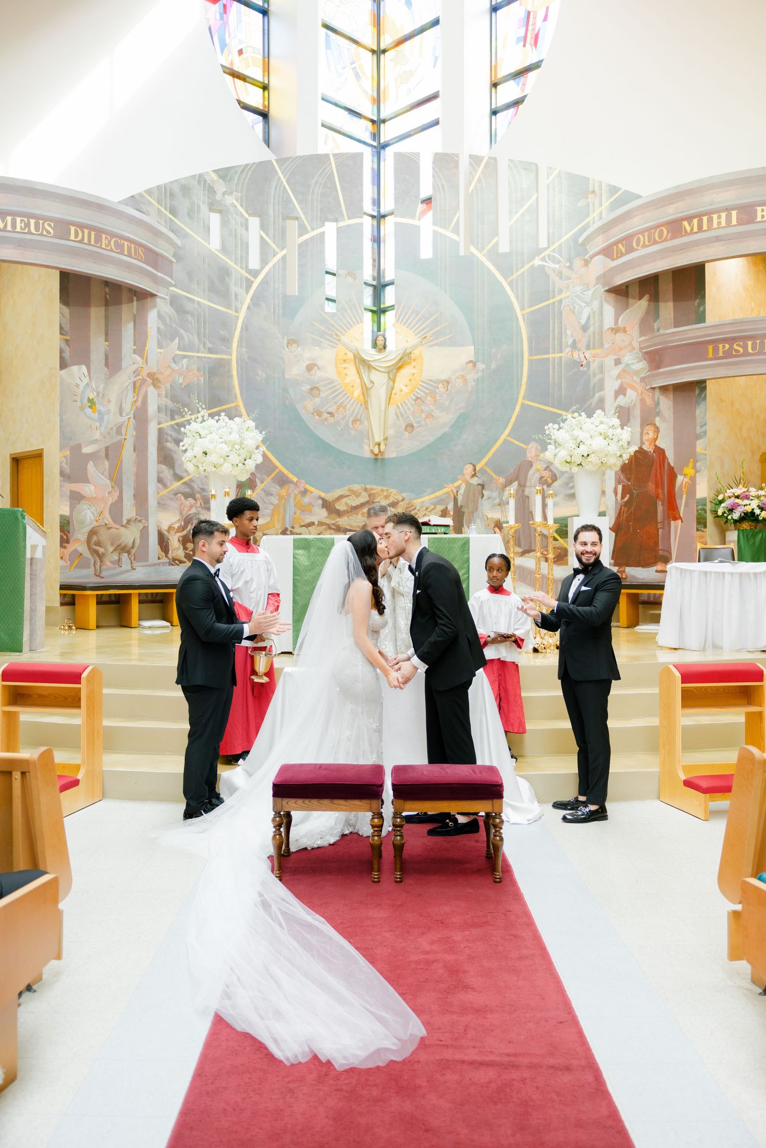 A Catholic church wedding ceremony with elegant decor and a stunning dove mural in the background.