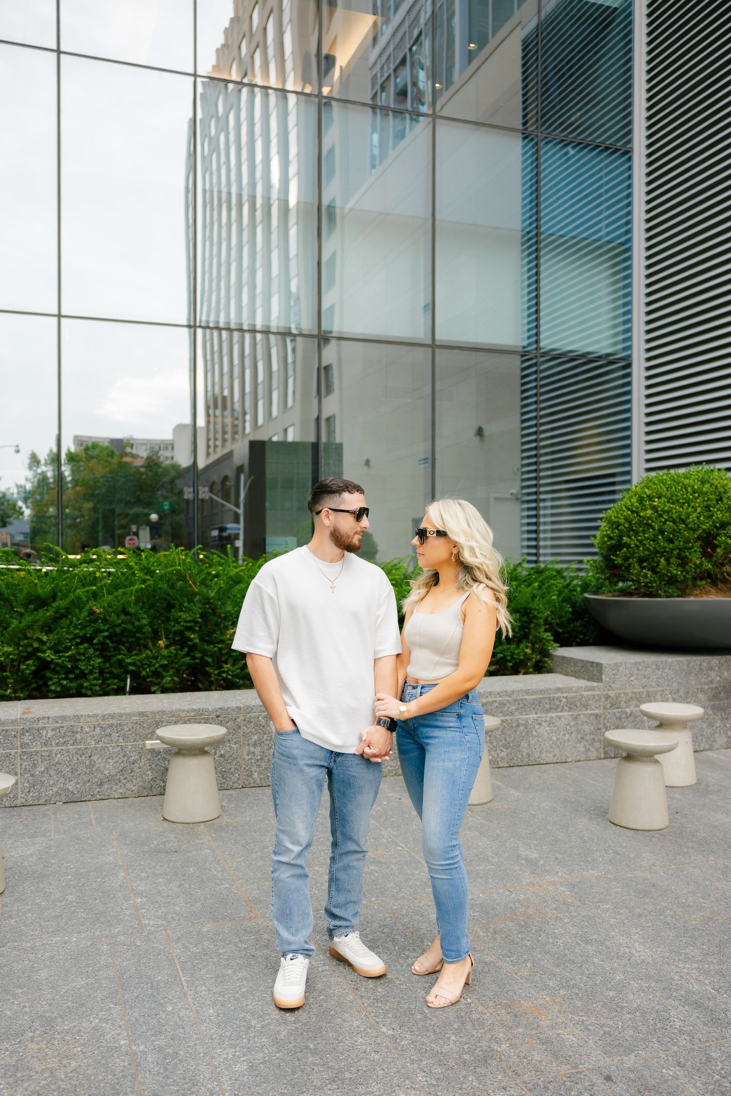 Full-length shot of couple in coordinated casual wear outside glass building.