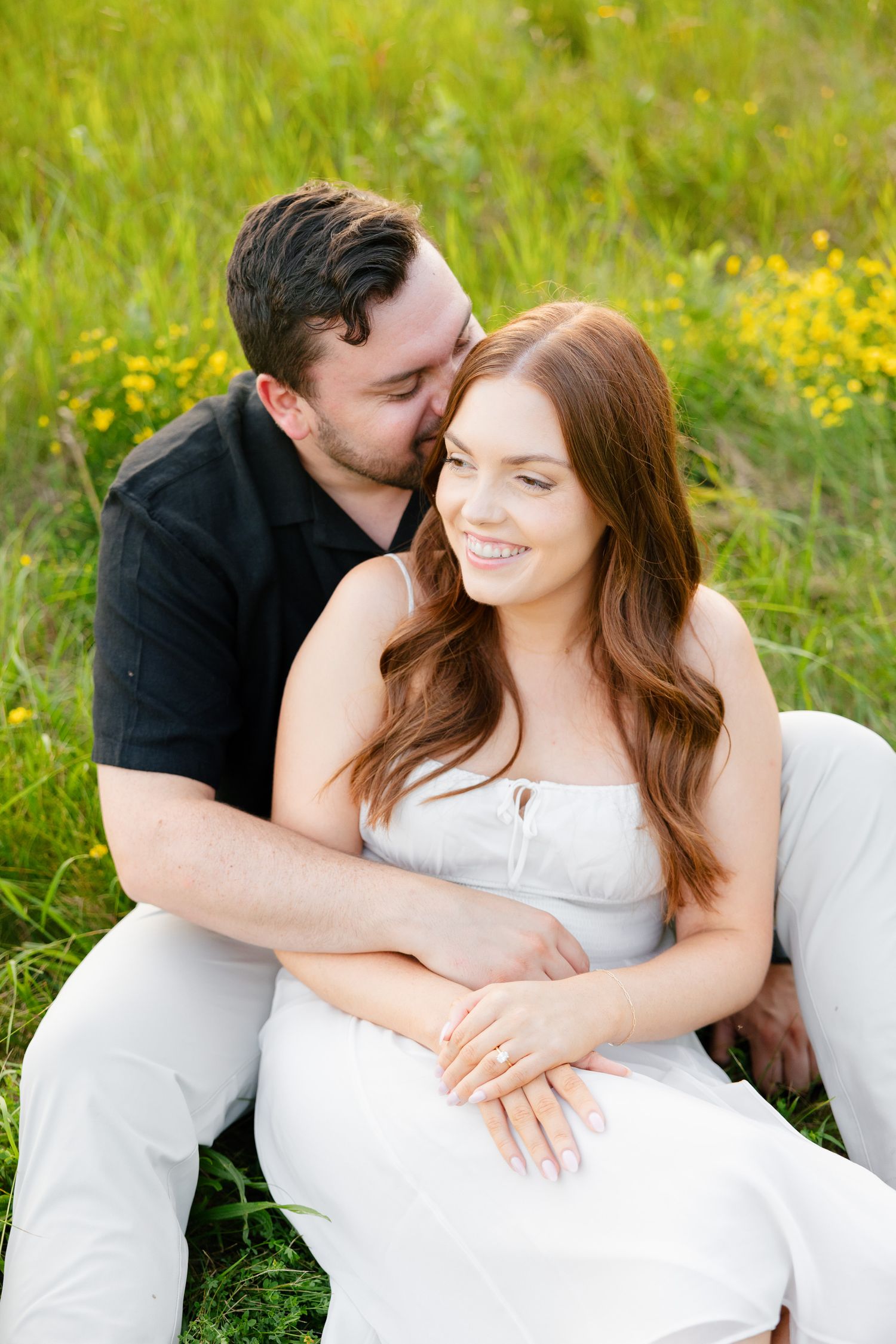 Tender moment captured between couple in sunlit wildflower field.