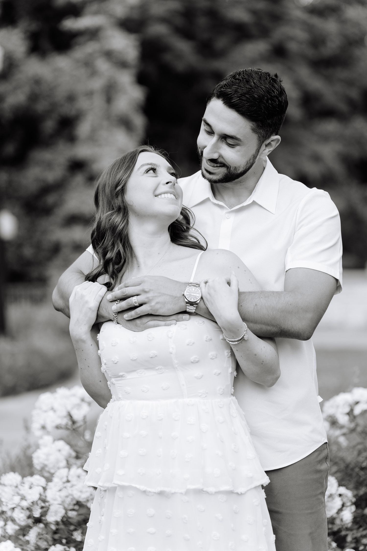 A black and white portrait of a couple sharing an intimate moment in a garden setting.