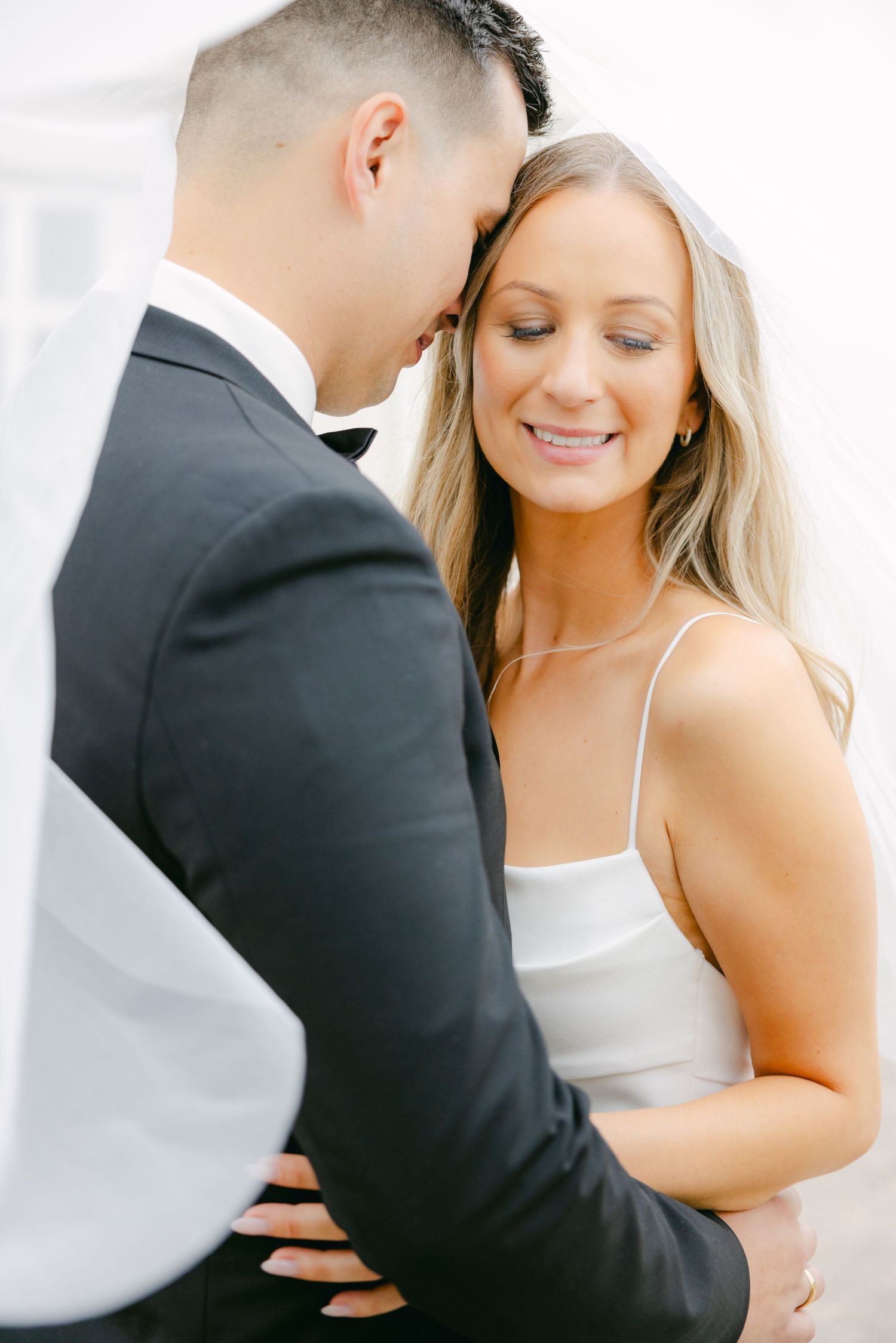 Intimate portrait of wedding couple sharing a tender moment in elegant attire.