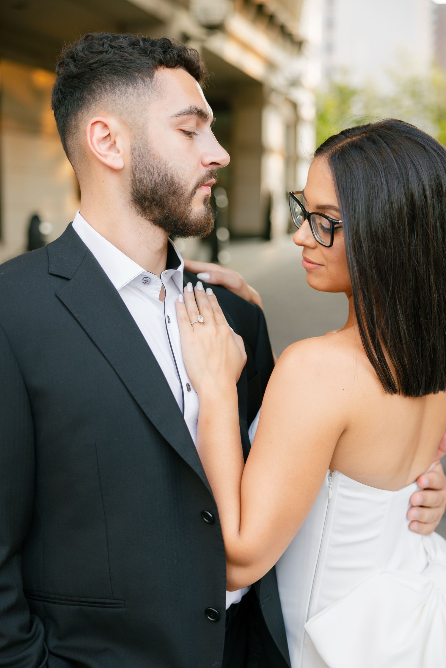 Intimate portrait of a couple in contrasting formal wear against modern architecture.