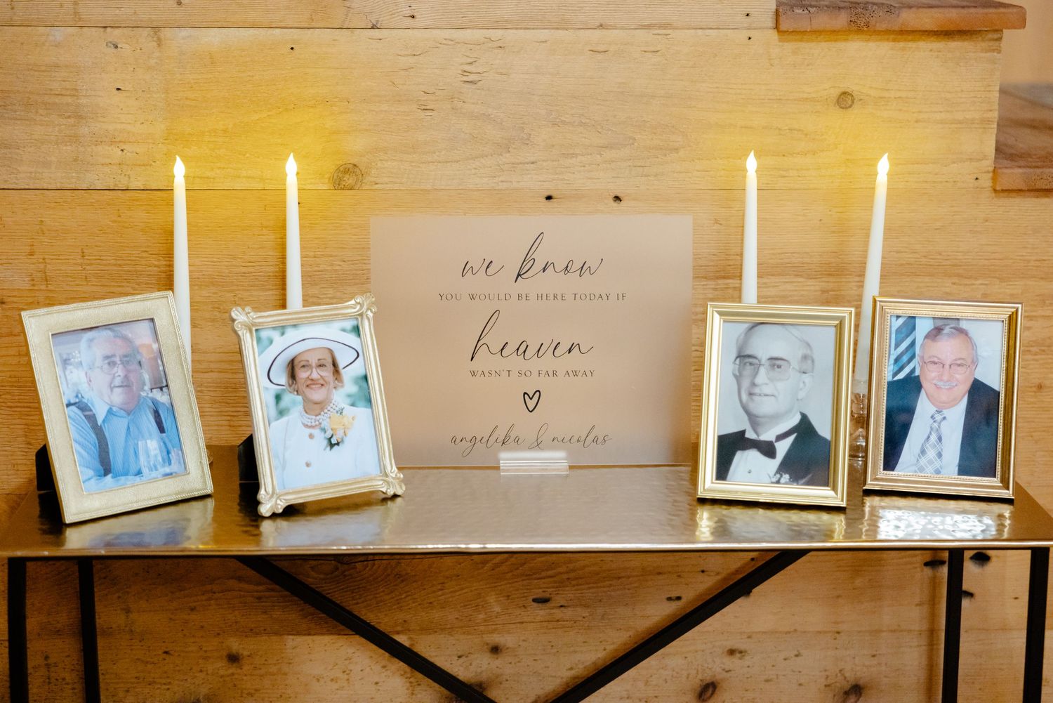 Memorial display with candles and framed photographs on wooden shelf.