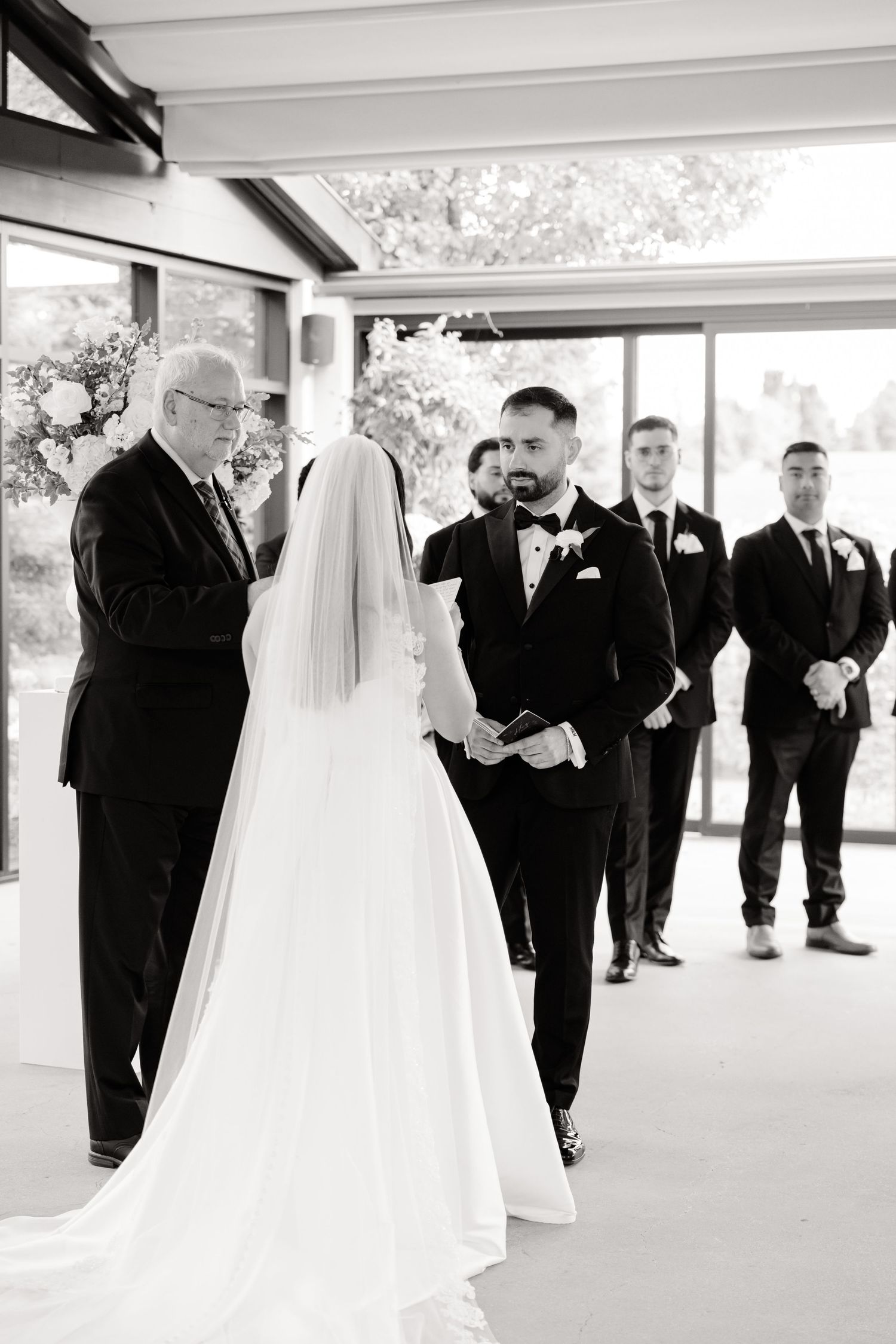 Black and white photo of wedding ceremony with groomsmen in formal attire.