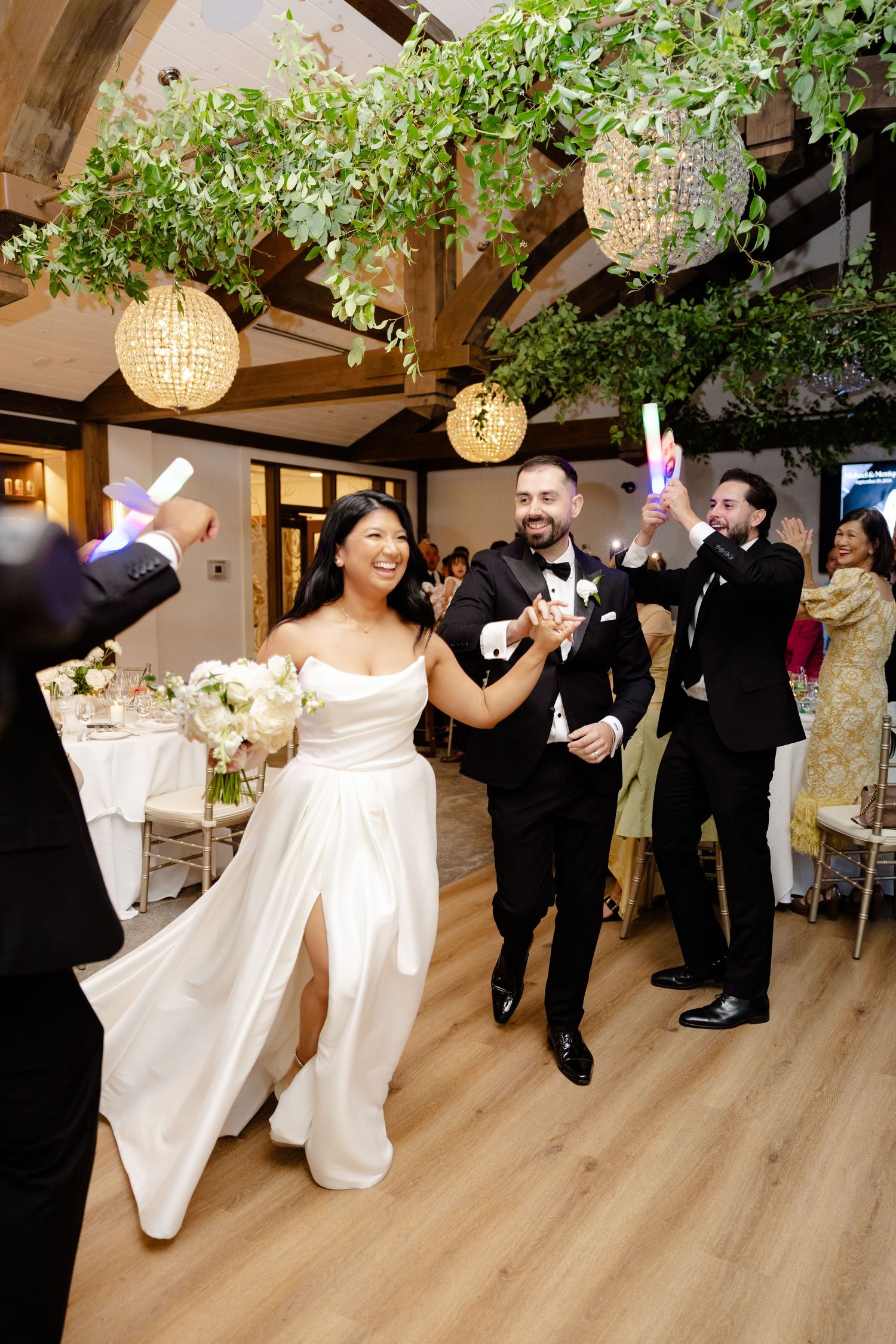 Guests cheer as the newlyweds dance during their reception in a rustic-elegant venue.