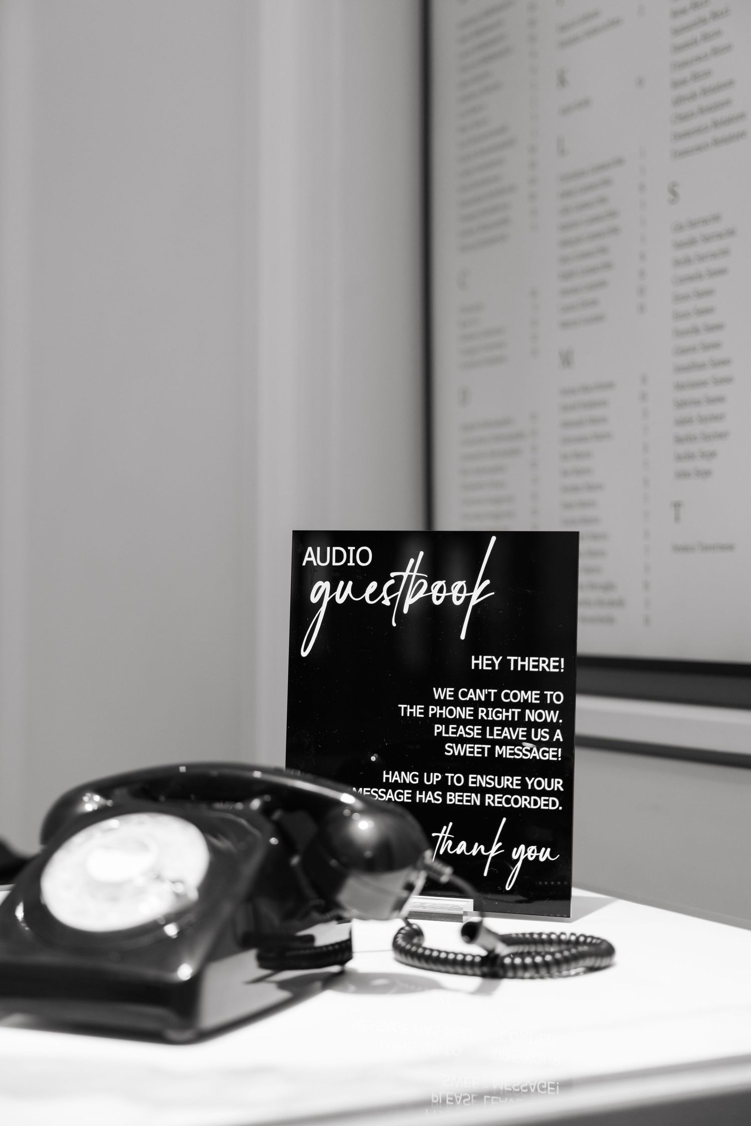 Vintage black rotary phone with guestbook sign in black and white photography.