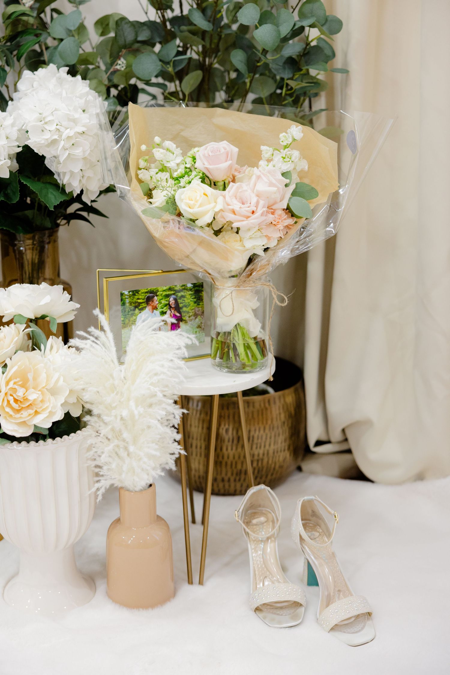 Wedding detail shot of bouquets, white heels, and floral arrangements on display.
