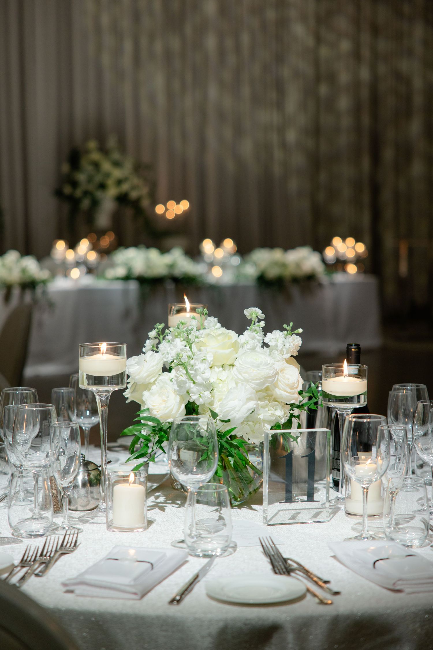 Intimate table setting with white floral centerpiece, candles and crystal glassware.