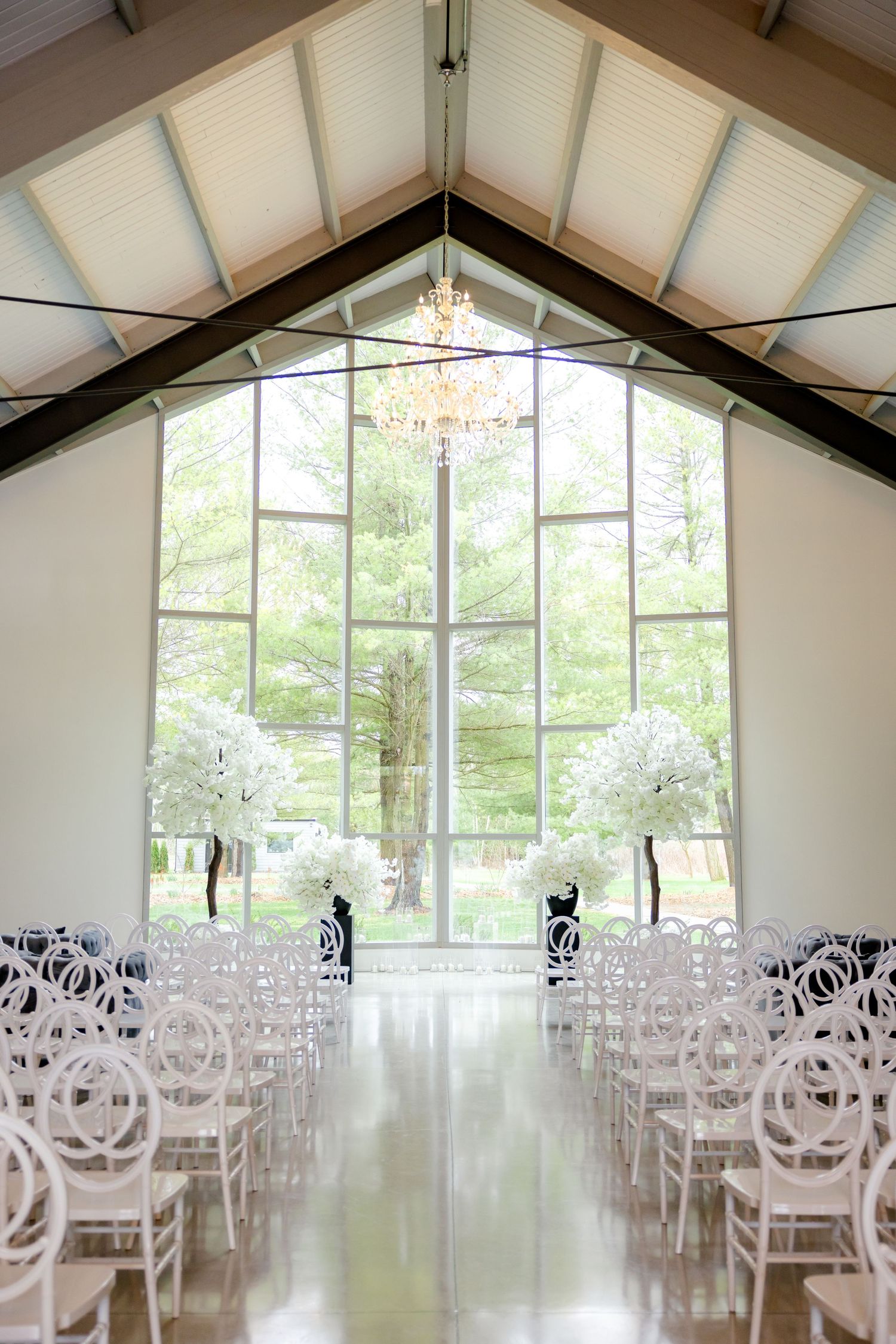 Modern chapel interior with vaulted ceiling, large windows and white chairs for wedding ceremony.
