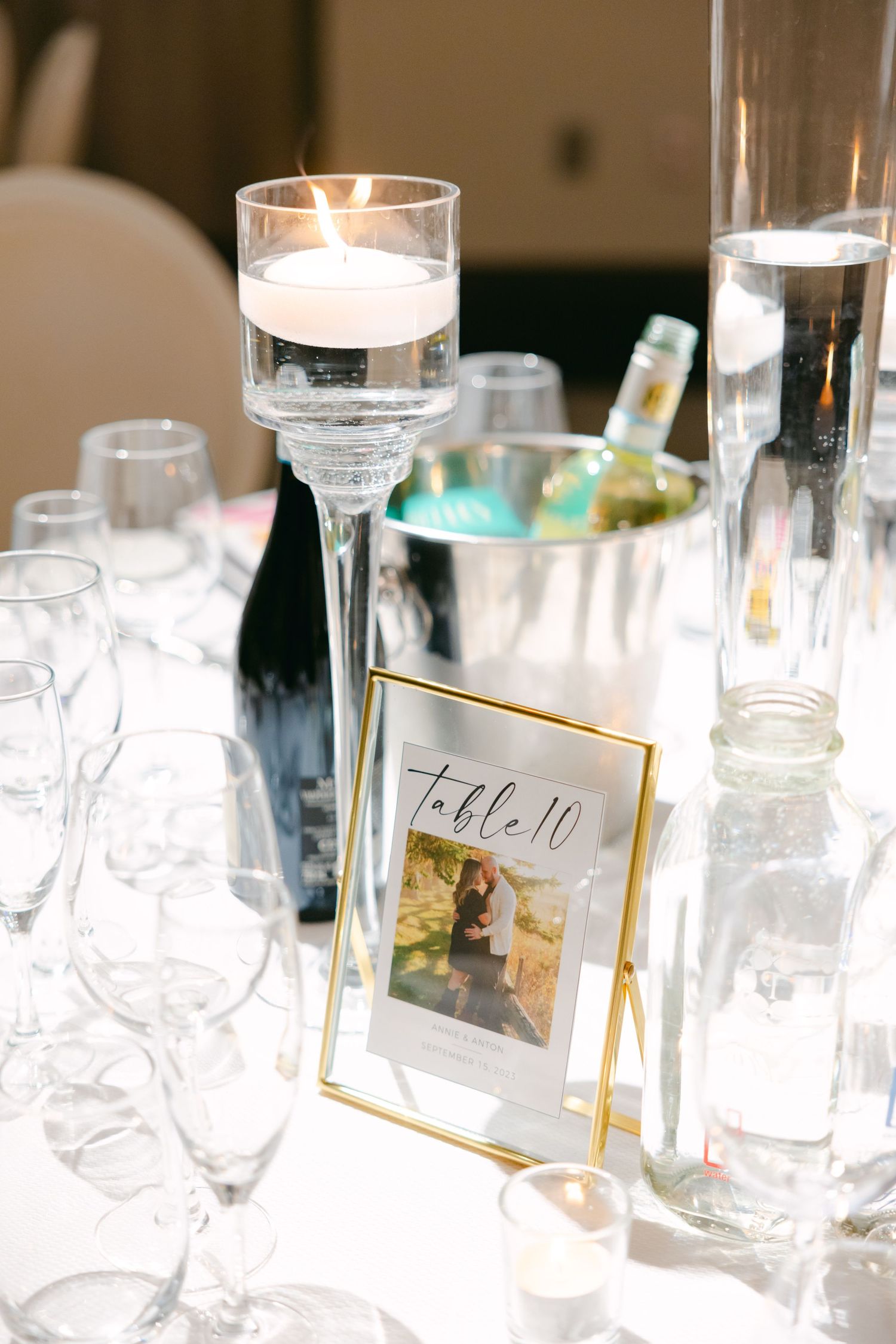 Wedding reception table detail with floating candle centerpiece and framed photograph.